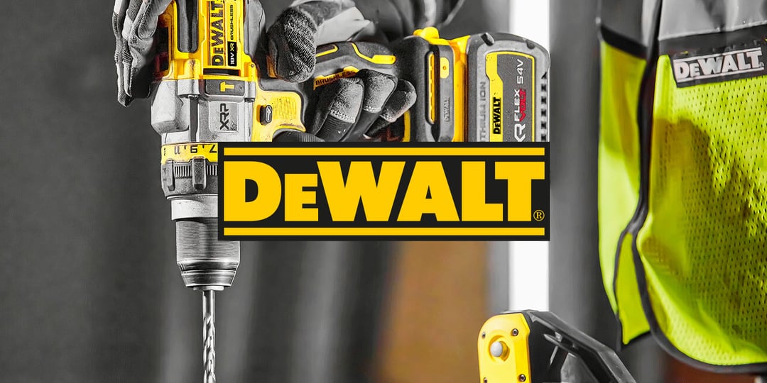 Närbild på en person som använder en gul och svart DeWalt borrmaskin, DeWalt logotyp i mitten av bilden. Ett annat verktyg och en skyddsväst i bakgrunden.