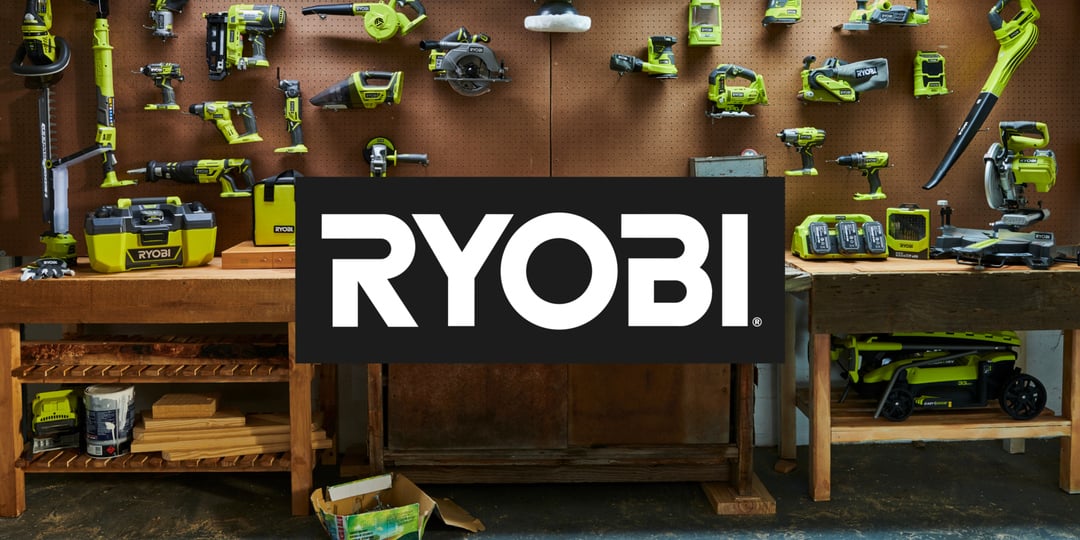 Gröna Ryobi elverktyg, batterier och laddare är organiserade på en pegboard och en arbetsbänk med Ryobi-logotypen i mitten.