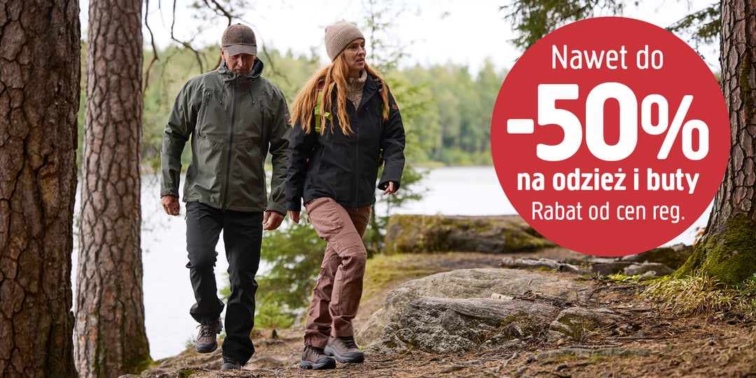 Mężczyzna i kobieta spacerujący leśną ścieżką nad jeziorem, a obok napis: Nawet do -50% na odzież i obuwie. Rabat od cen regularnych.
