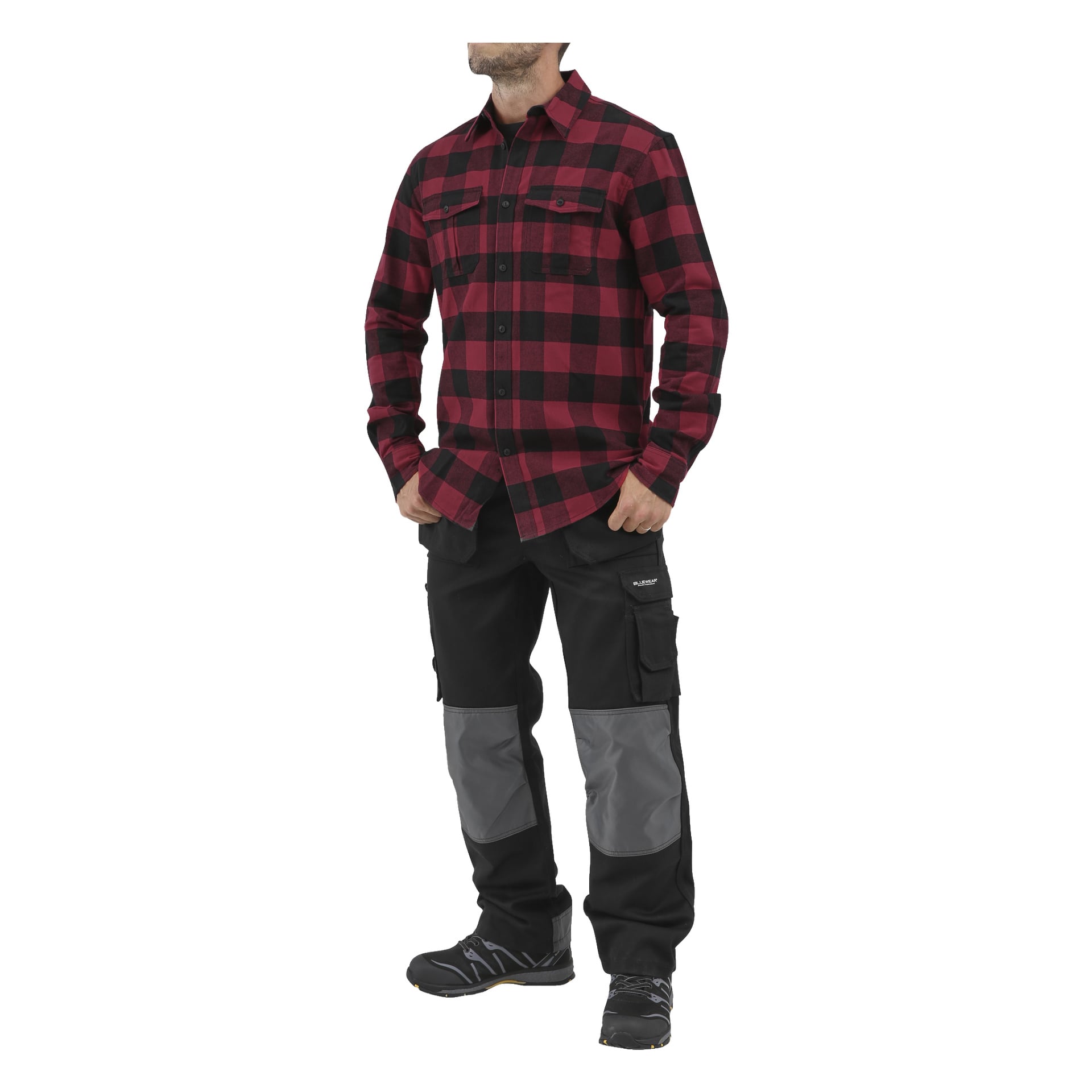 En mann står med hendene i lommene, kledd i en rød og svart rutete Bluewear Men's flanellskjorte.