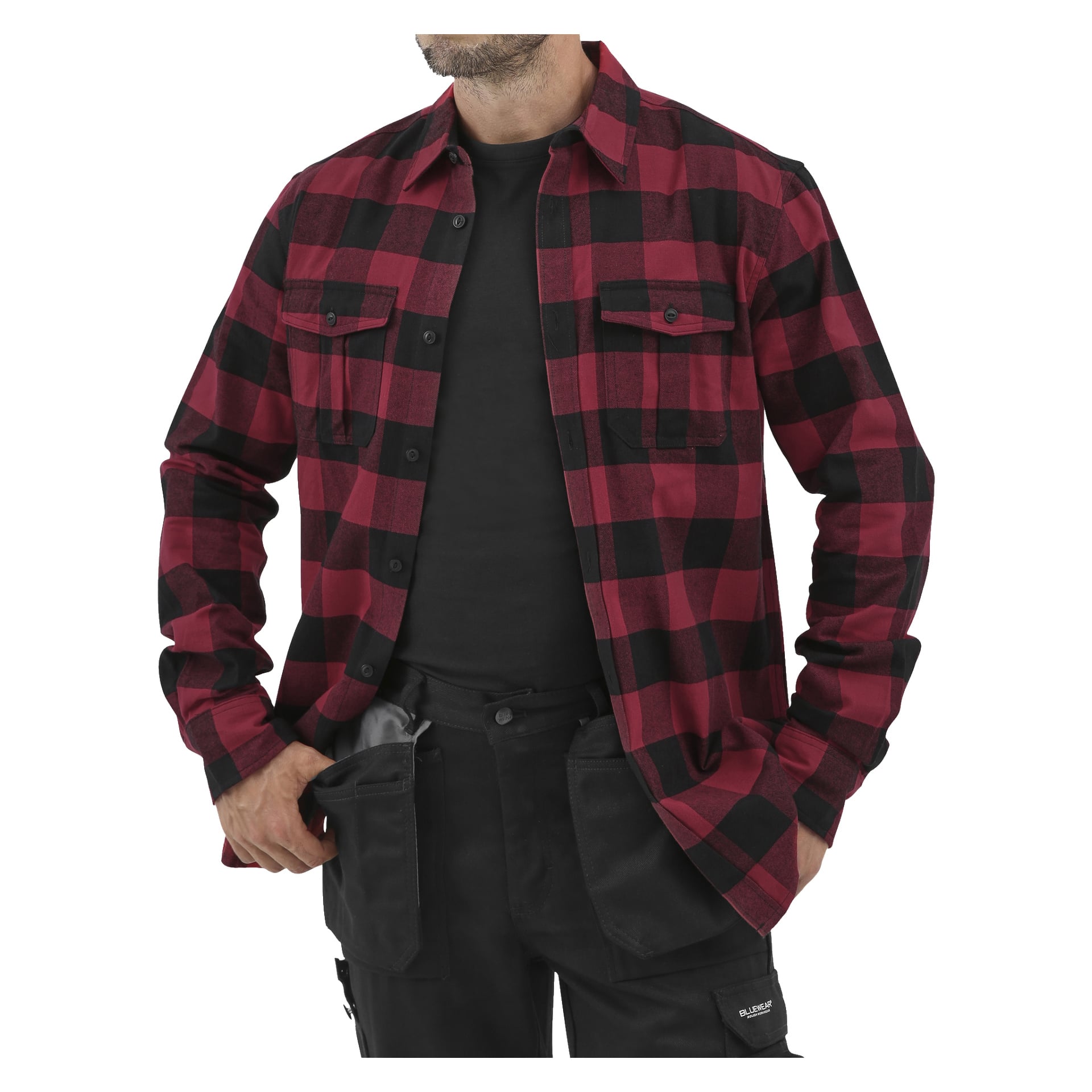 Mężczyzna prezentuje czerwono-czarną flanelową koszulę Bluewear Bluewear w kratę, nałożoną na t-shirt, połączoną z czarnymi wielokieszeniowymi spodniami roboczymi.