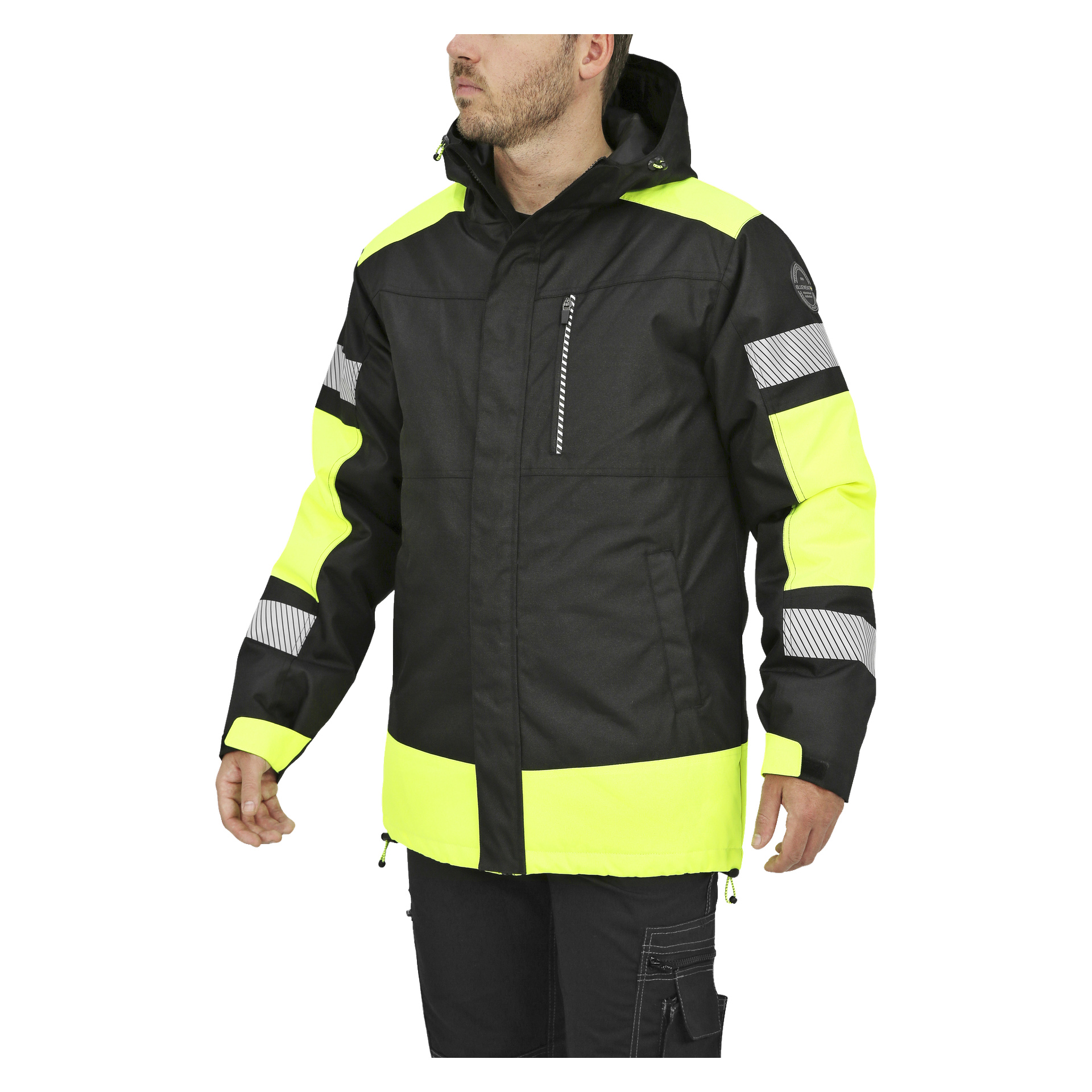 En person klädd i Bluewear Parka med svarta och neongula paneler, reflekterande ränder på armar och bröst, tillsammans med svarta byxor och huva, står med armarna något utsträckta.