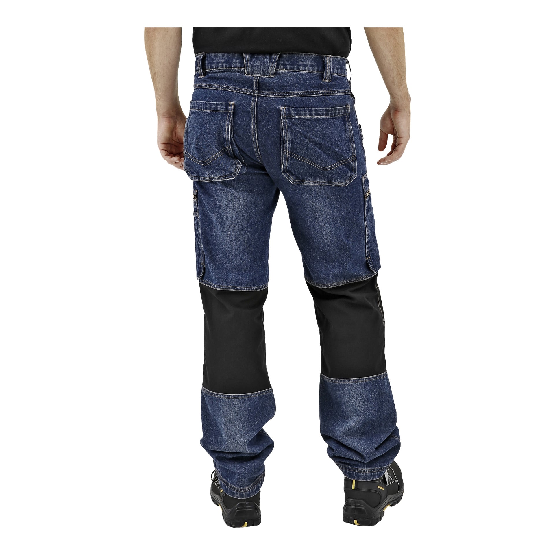Od tyłu osoba nosi niebieskie dżinsowe spodnie robocze Bluewear Mens z czarnymi wzmocnionymi naszywkami na kolanach, czarną koszulę i czarne buty robocze. Spodnie mają kilka kieszeni i solidne szwy, co podkreśla ich wytrzymałość do wymagających zadań.
