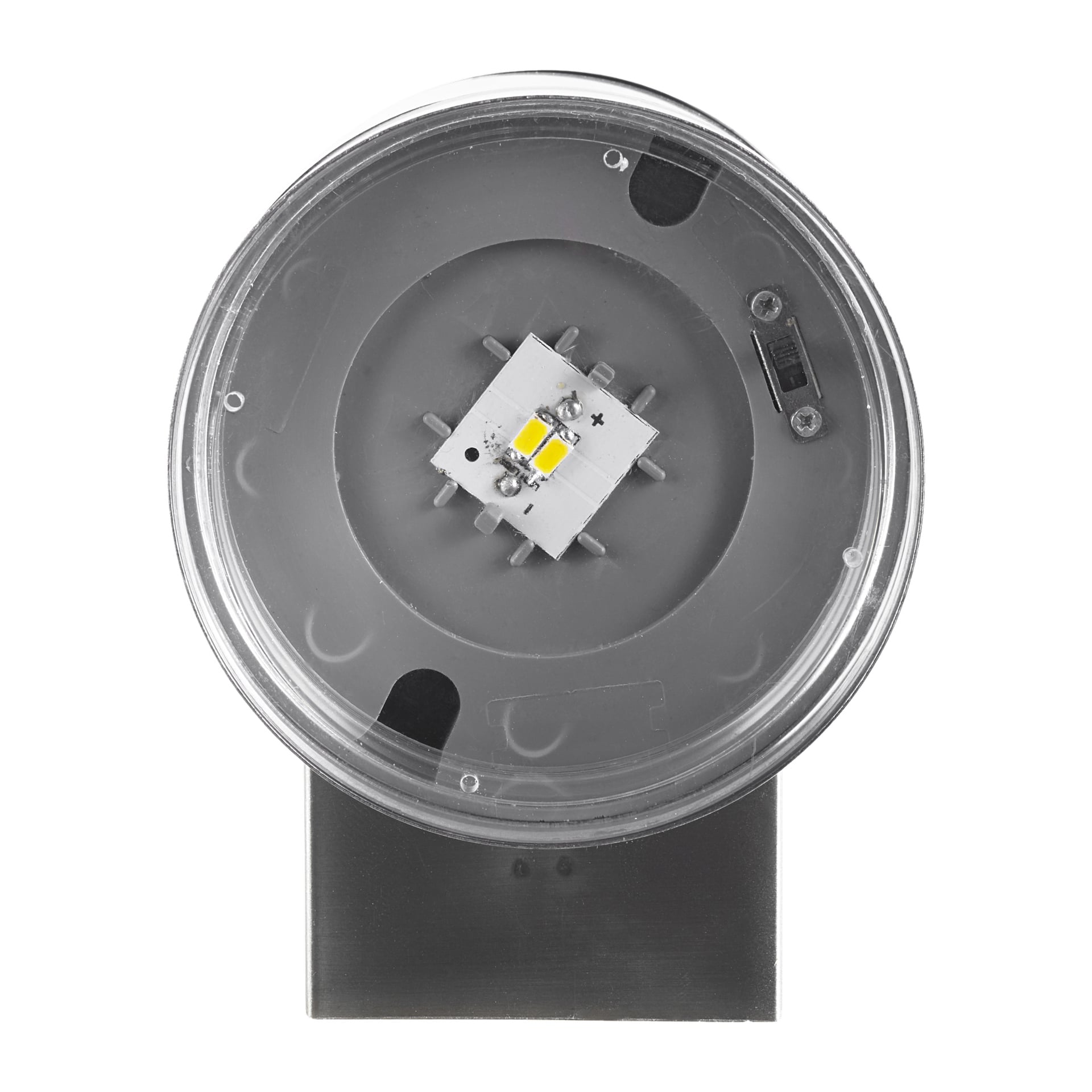 Nærbilde av Anslut vegglampe-LED med et rundt, klart plastdeksel som viser LED-kretskortet inni, som har to gule dioder og markeringer for positive og negative forbindelser på en grå base.