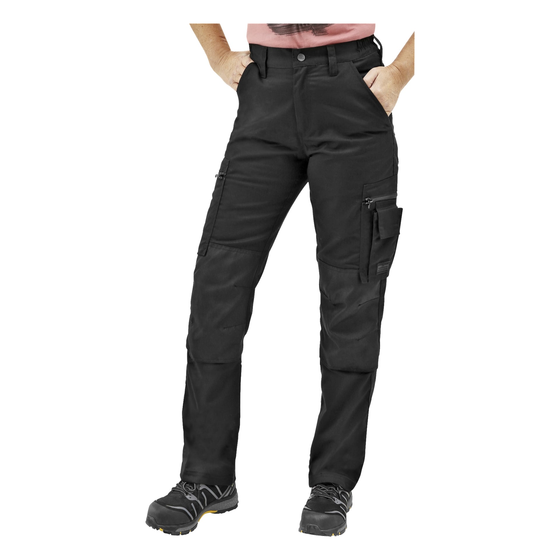 Eine Person trägt Bluewear Damen-Diensthosen mit mehreren Taschen und verstärkten Knien sowie ein rosa Hemd und schwarze Schuhe. Die Hände sind in den Hosentaschen, und das Bild ist von Schultern bis zu Füßen zugeschnitten.