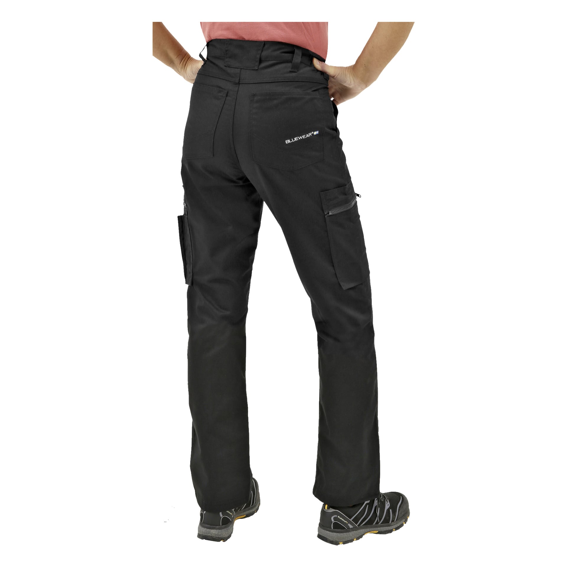 Eine Person steht mit dem Rücken zur Kamera, gekleidet in Bluewear Damen-Servicehosen mit Reißverschlusstaschen, einem eingesteckten roten Hemd und schwarzen Schuhen mit gelben Akzenten. Die rechte Gesäßtasche zeigt das Bluewear-Logo.