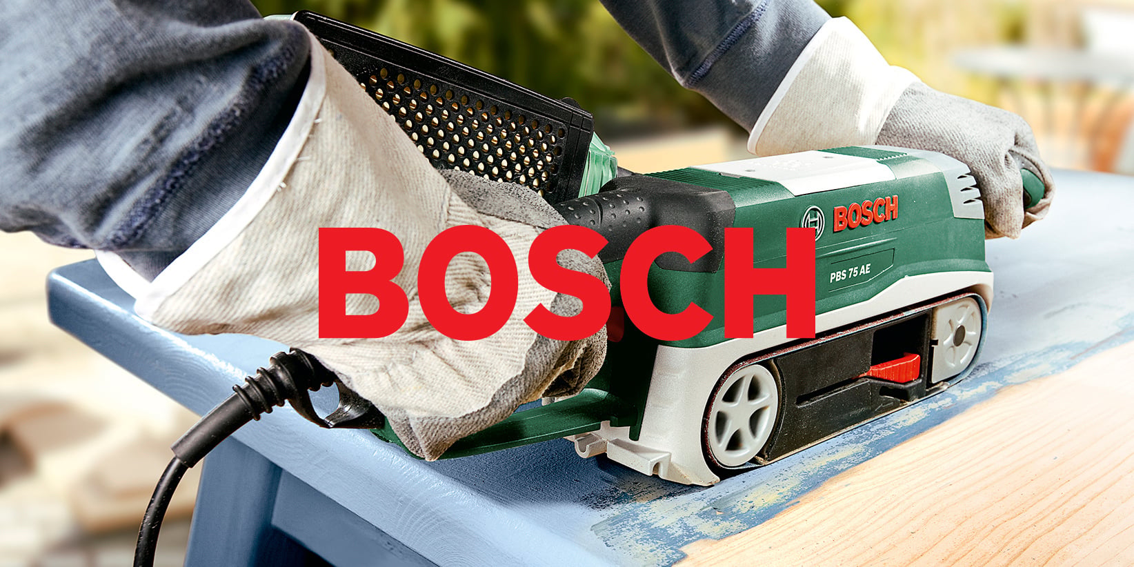 En person med handskar slipar trä med en grön Bosch elektrisk slipmaskin. Stora röda bokstäver som stavas BOSCH är överlagrade i mitten.