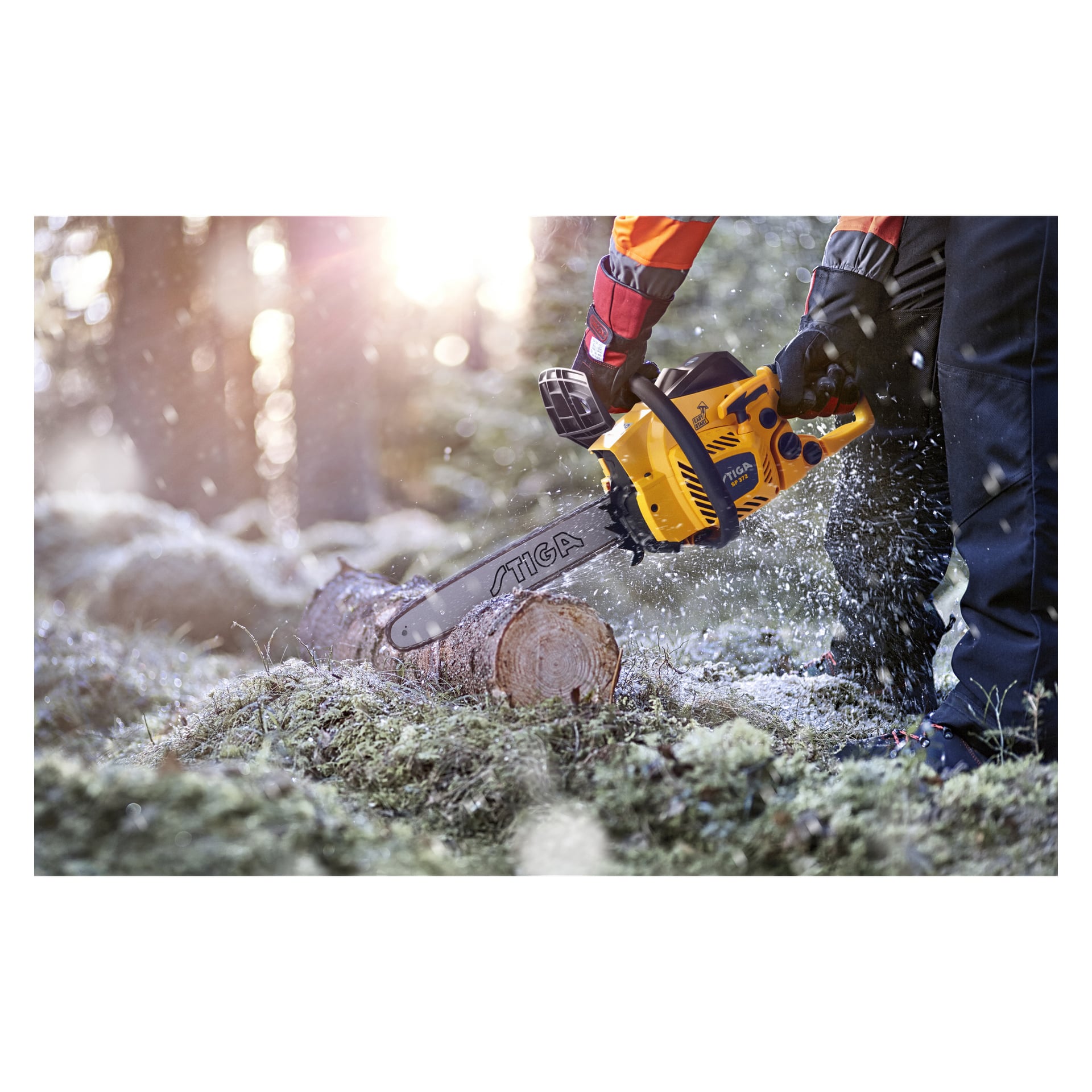Osoba ubrana w rękawice robocze i odzież outdoorową obsługuje piłę łańcuchową Stiga SP 372, przecinając kłodę wśród drzew, gdzie promienie słońca wpadają, a trociny unoszą się wokół.