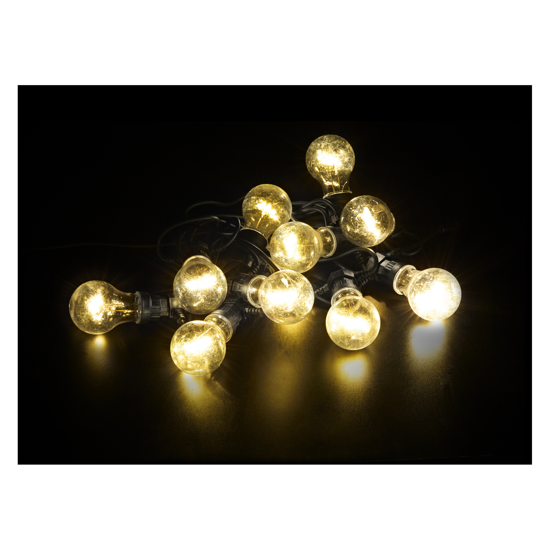 Grupa lamp LED Anslut Party z okrągłymi żarówkami leży na błyszczącej czarnej powierzchni, emitując miękkie żółte światło w ciemności.