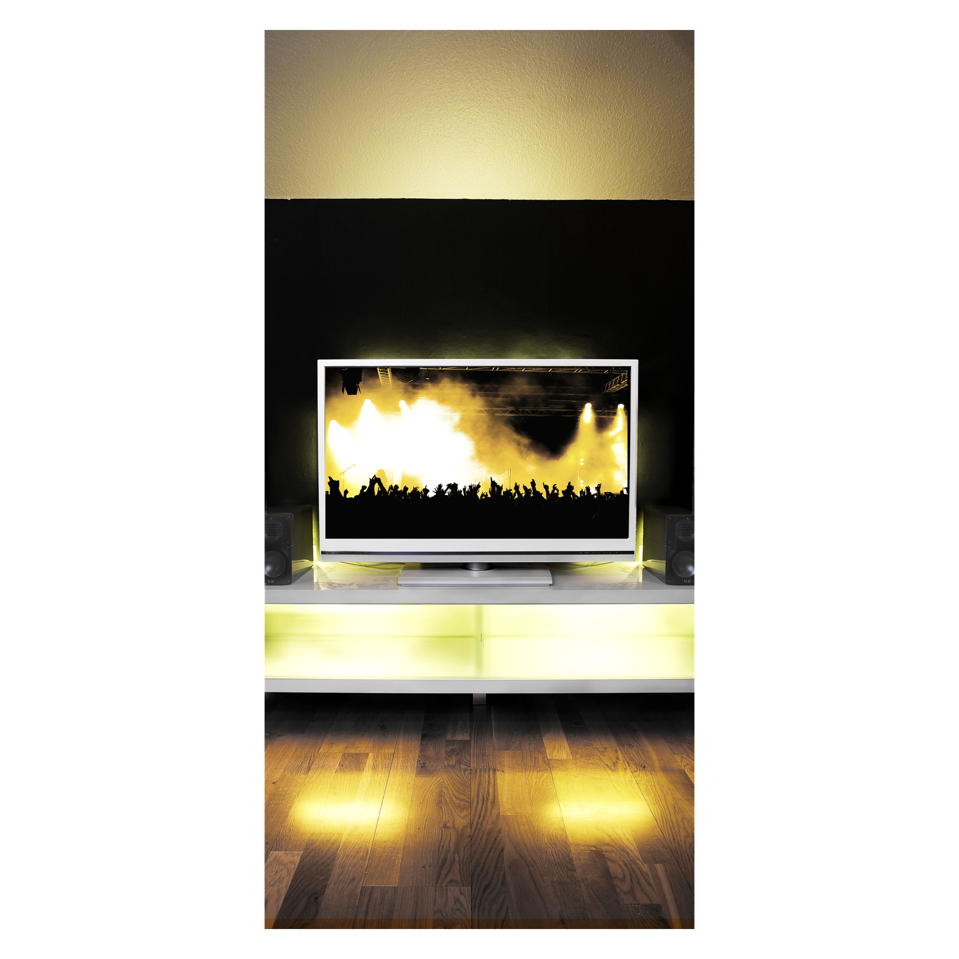 Ein sanftes gelbes Licht einer Anslut RGB-LED leuchtet unter einem Flachbildfernseher und zeigt ein Konzert mit gelben Bühnenlichtern und Publikumssilhouetten. Der Fernseher steht auf einem weißen Regal, flankiert von zwei Lautsprechern, wobei alles auf einem Holzboden steht.