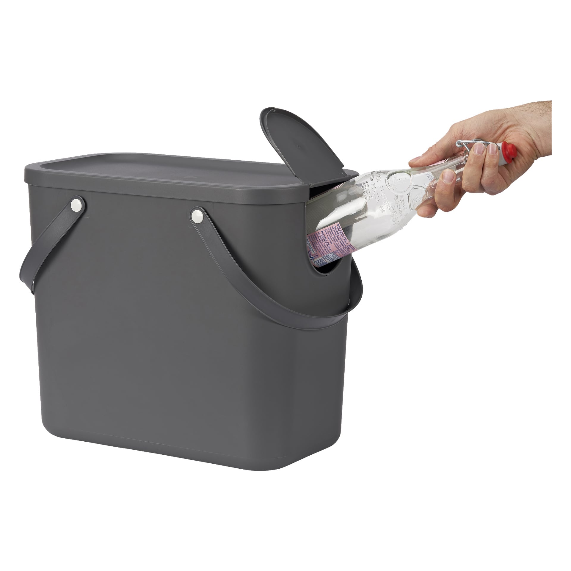 En hand syns som stoppar in en klar glasflaska i en Hard Head Recycling-behållare med ett delvis öppet mörkgrått lock och två handtag på sidorna.