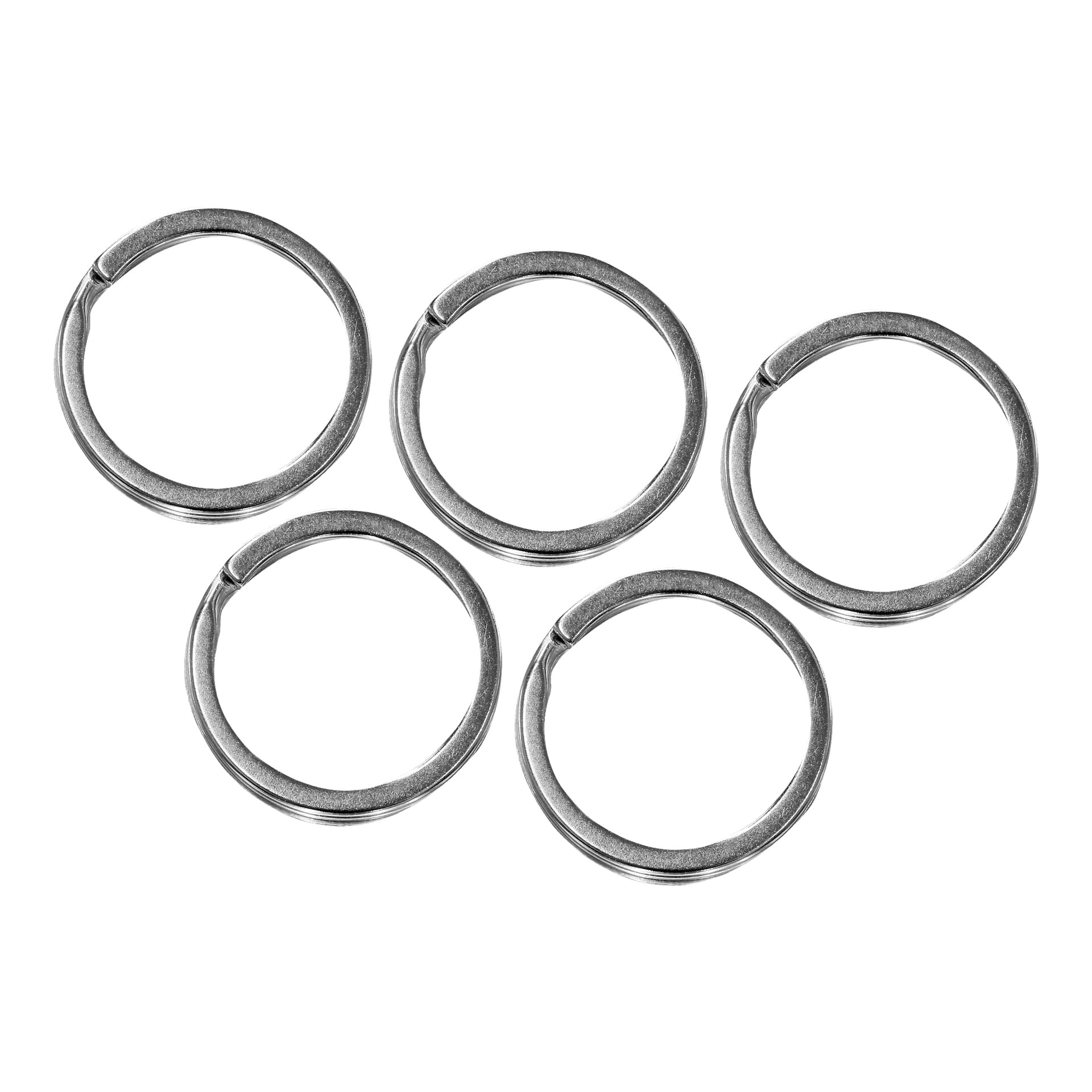 Pięć srebrnych metalowych breloczków Hard Head z zestawu Key Rings 5 jest równomiernie rozmieszczonych. Każdy pierścień ma niewielką szczelinę na końcach do mocowania kluczy lub przedmiotów, a są one ułożone w dwóch rzędach.