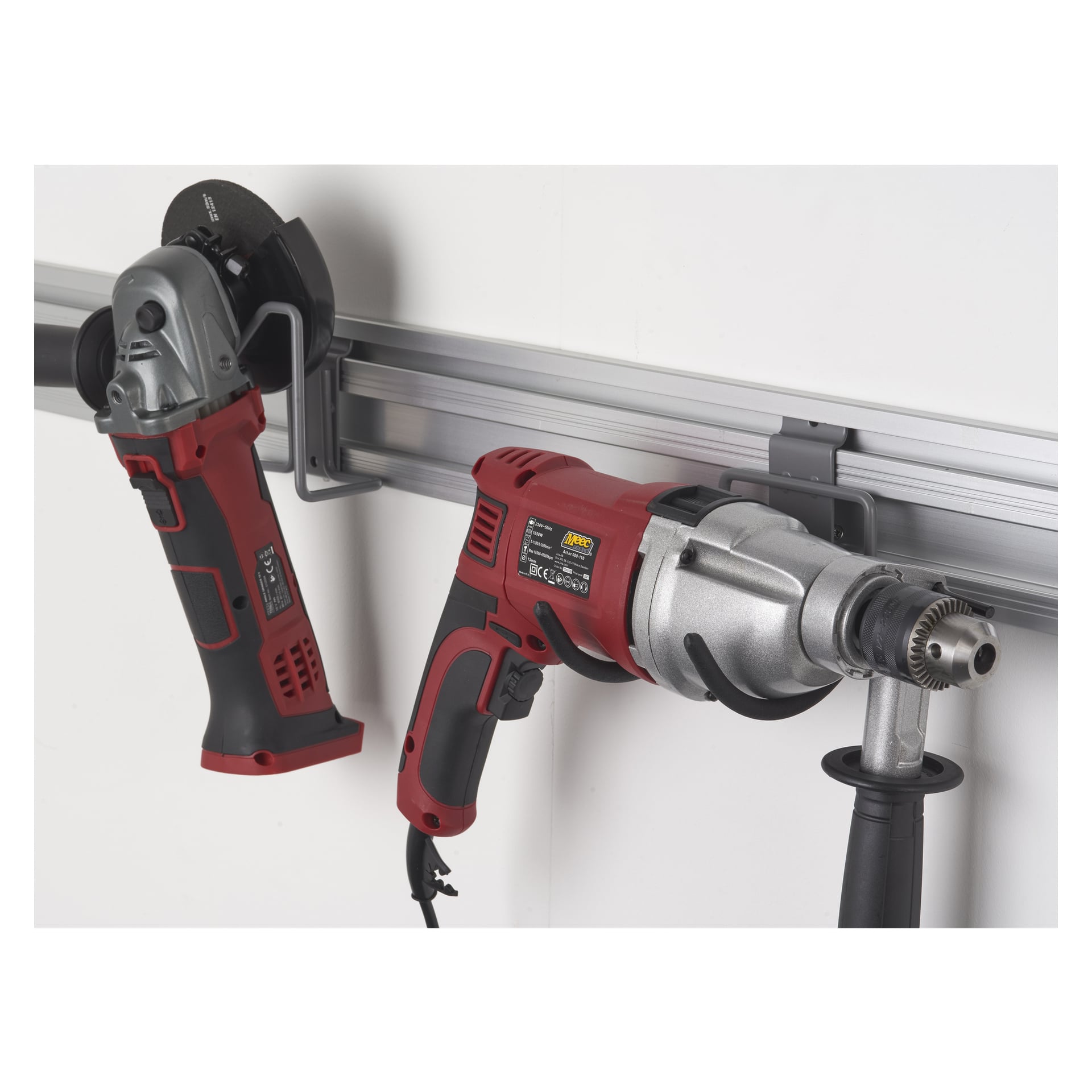 Hak Hard Head Tool do wiertarki młotkowej jest przymocowany do metalowej szyny, pewnie trzymając czerwono-czarną szlifierkę kątową obok przewodowej wiertarki elektrycznej w pozycji pionowej.