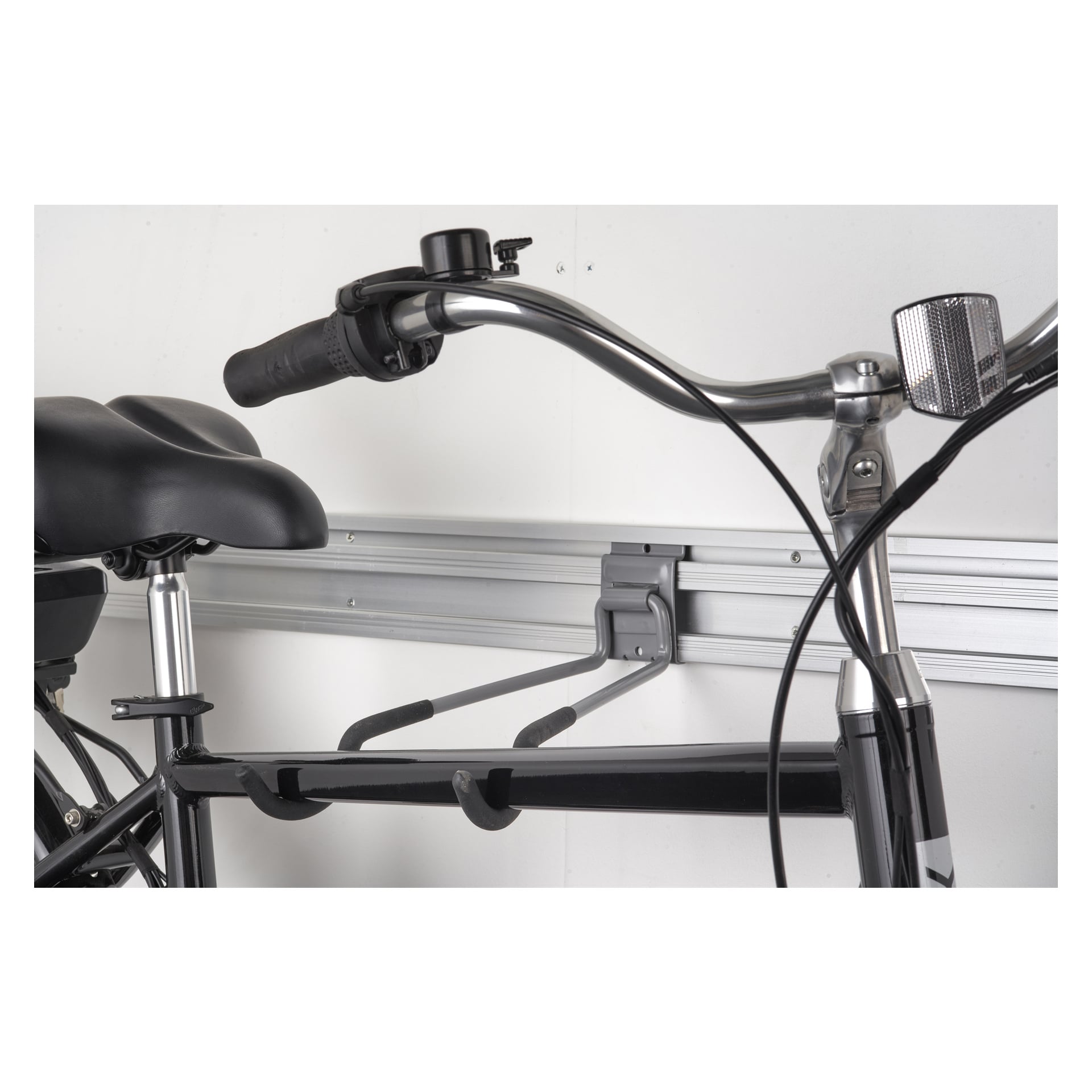 Hard Head Holder do roweru jest zamontowany poziomo na ścianie garażu z metalowym szynem, który mocno podtrzymuje rower z kierownicą i siedzeniem widocznymi w widoku.