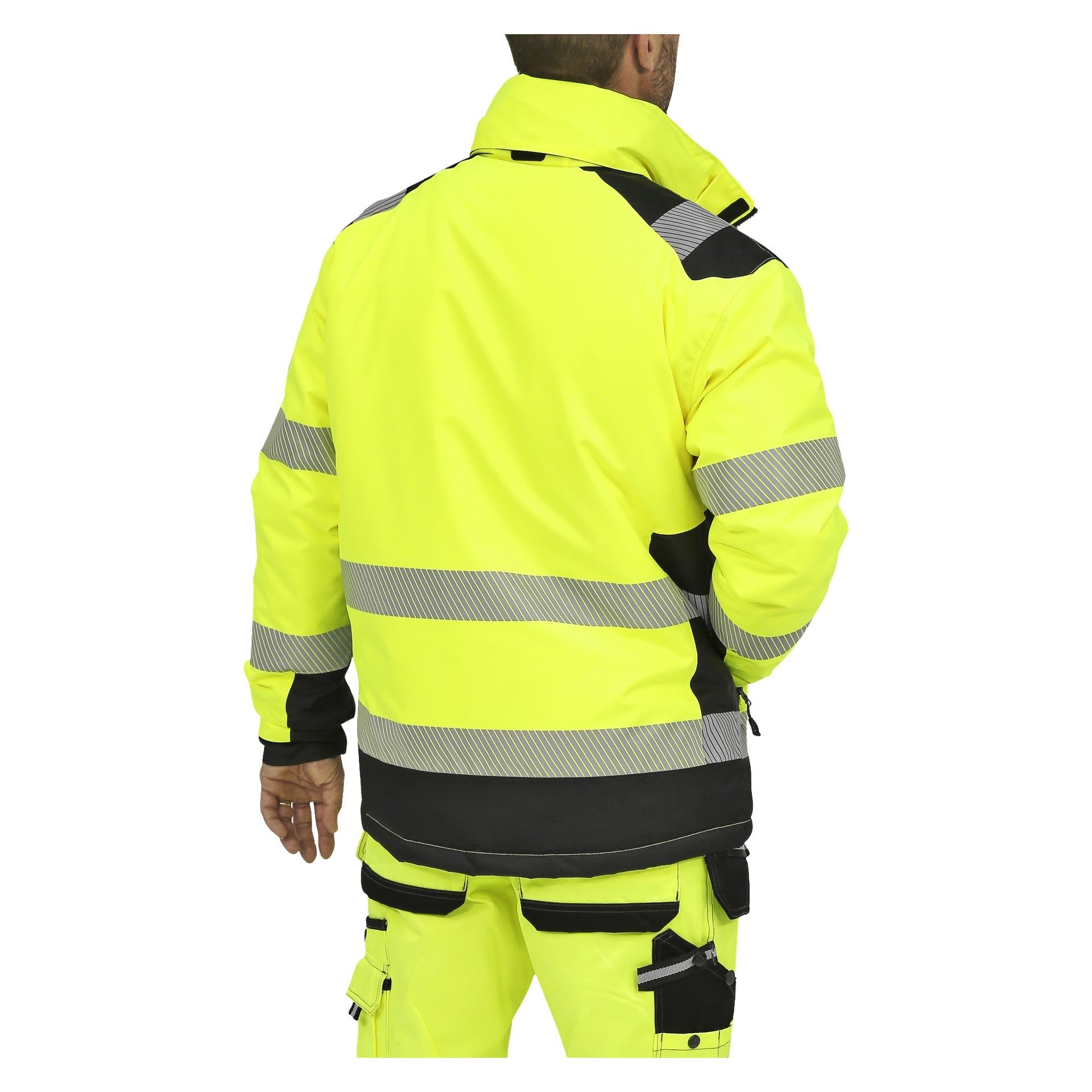 Eine Person steht mit dem Rücken zur Kamera, gekleidet in eine neongelbe Bluewear Warm gefütterte Hi-Vis-Jacke mit horizontalen grauen reflektierenden Streifen und schwarzen Details sowie passenden neongelben Arbeitshosen mit schwarzen Utility-Taschen.