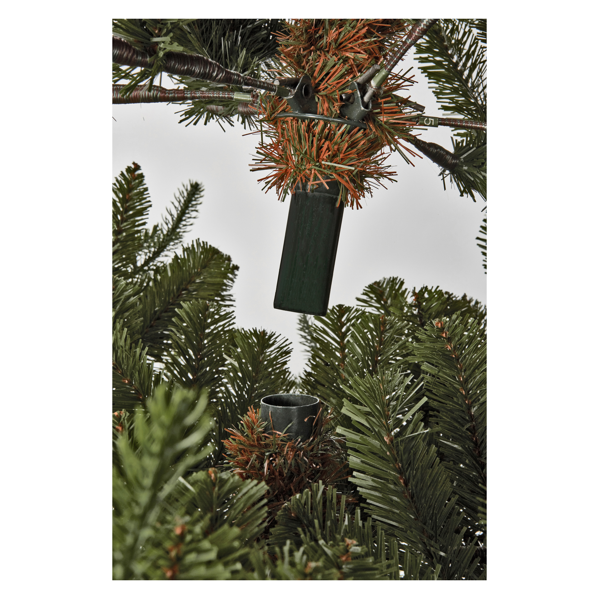 Nærbilde av to grener fra EKVIP Lifelike premium juletreet, den ene med en grønn plastplugg og den andre en tilsvarende pipe for enkel montering.