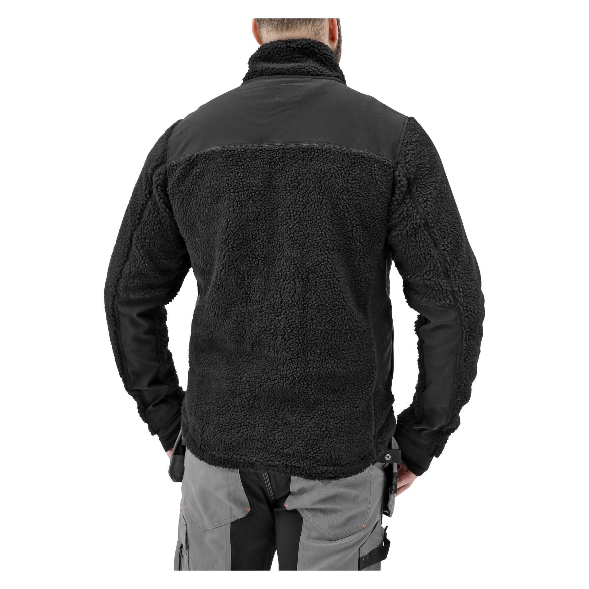 En person står med ryggen mot kameran, klädd i en svart Bluewear Pro Workwear herrjacka med fiberpäls och ett texturerat utseende och grå byxor. Deras händer vilar på höfterna och verktygen är fästa vid byxorna.