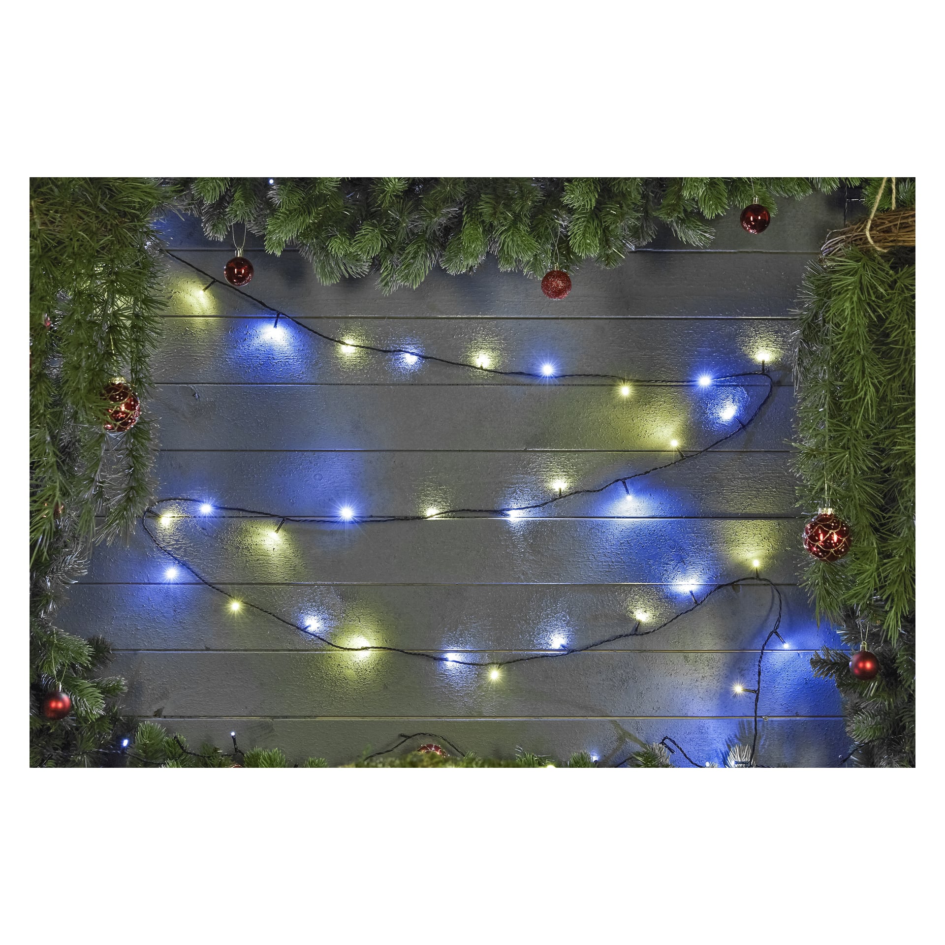 Grön girland och röda prydnader hänger över en trävägg, accentuerade av EKVIP LED-ljusslingor i blått och vitt som zickzackar mjukt över ytan. Frodig grönska ramar in toppen och sidorna av displayen.