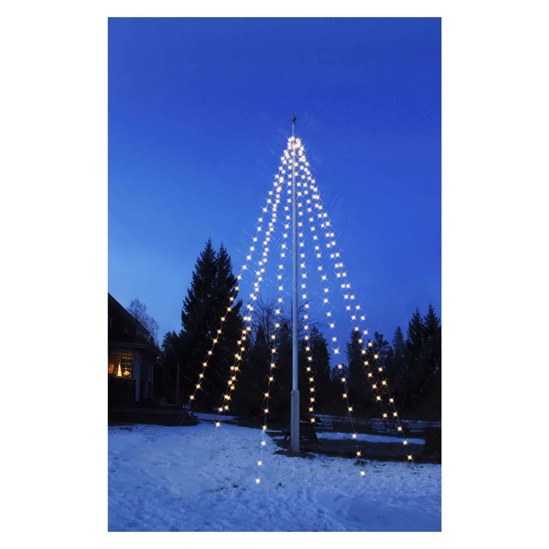 En hög EKVIP-flaggstångskedja av LED-ljus bildar en julgransform utomhus på snö i skymningen, med ett hus och träd i bakgrunden.
