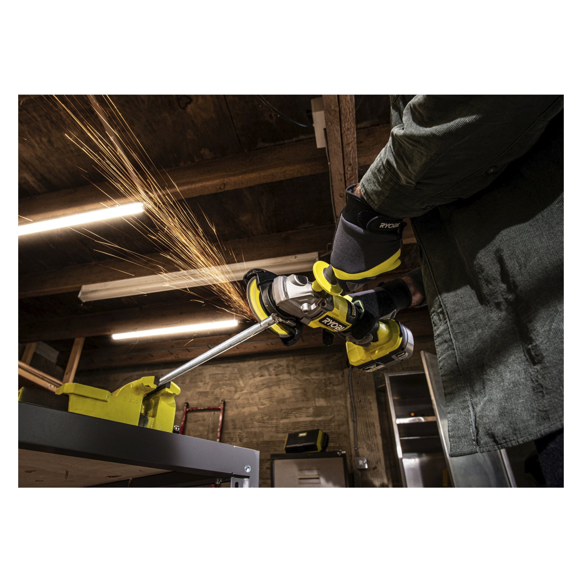 Osoba w rękawiczce obsługuje szlifierkę kątową Ryobi One+ HP RAG18X-140SJ na metalowym prętze w warsztacie, generując iskry podczas szlifowania.