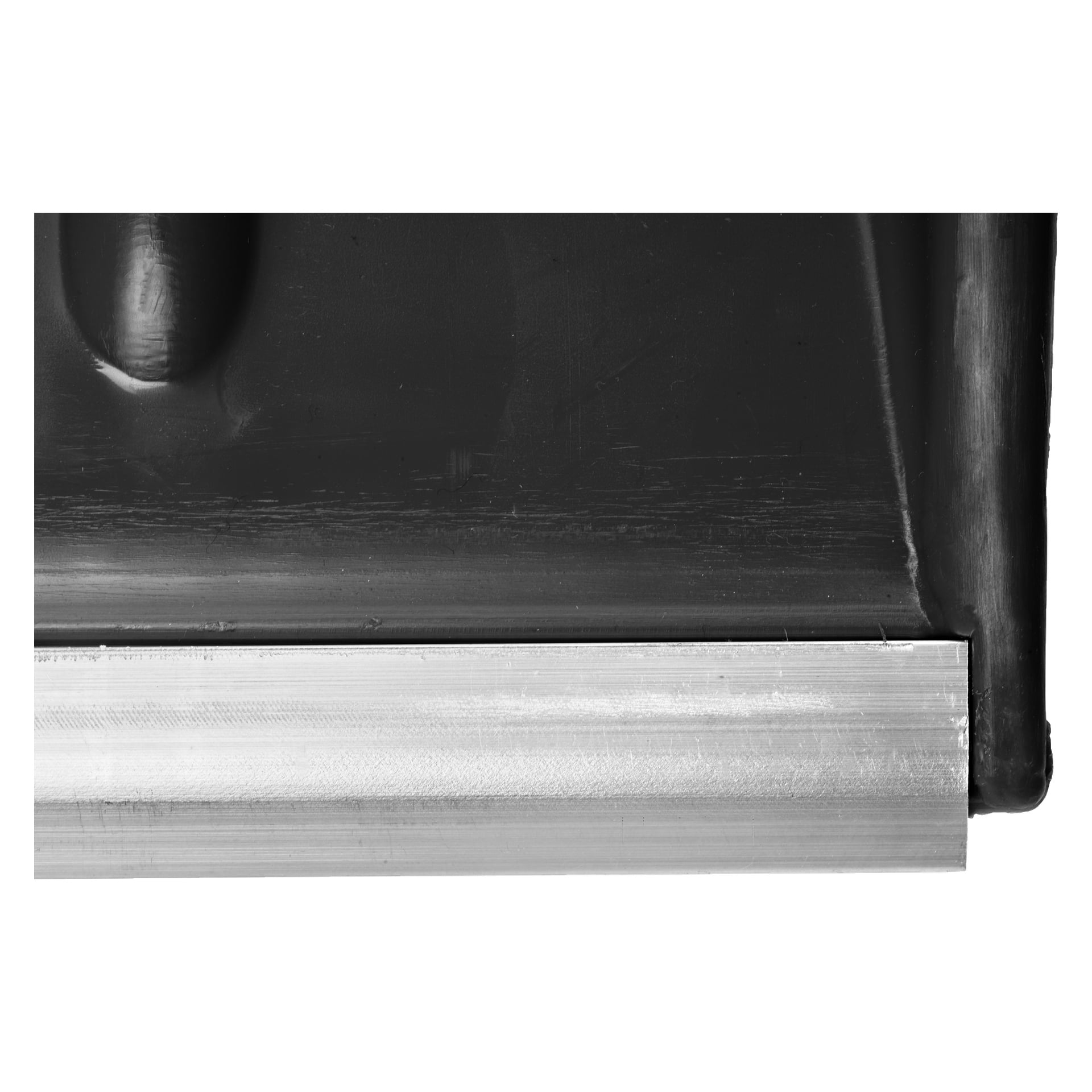 Närbild på en Hard Head-snöspade med aluminiumhandtag, med fokus på den raka metallkanten i nivå med undersidan av dess blanka svarta blad. Fina repor och en blank, lätt reflekterande yta syns.