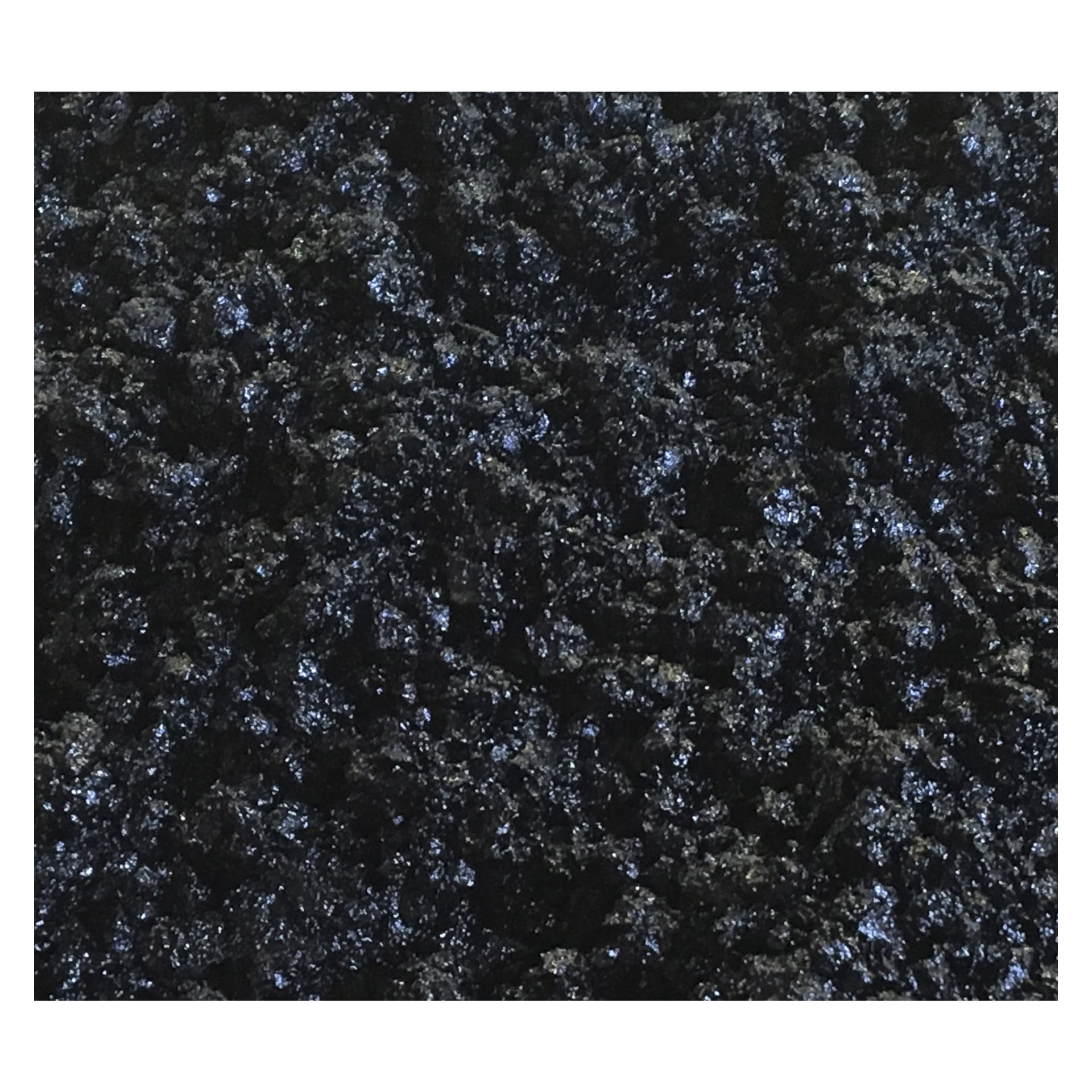 Hard Head Asphalt Repair-ytan visas i närbild, med en mörk, grov textur med en svag glans och utspridda blå och svarta prickar.