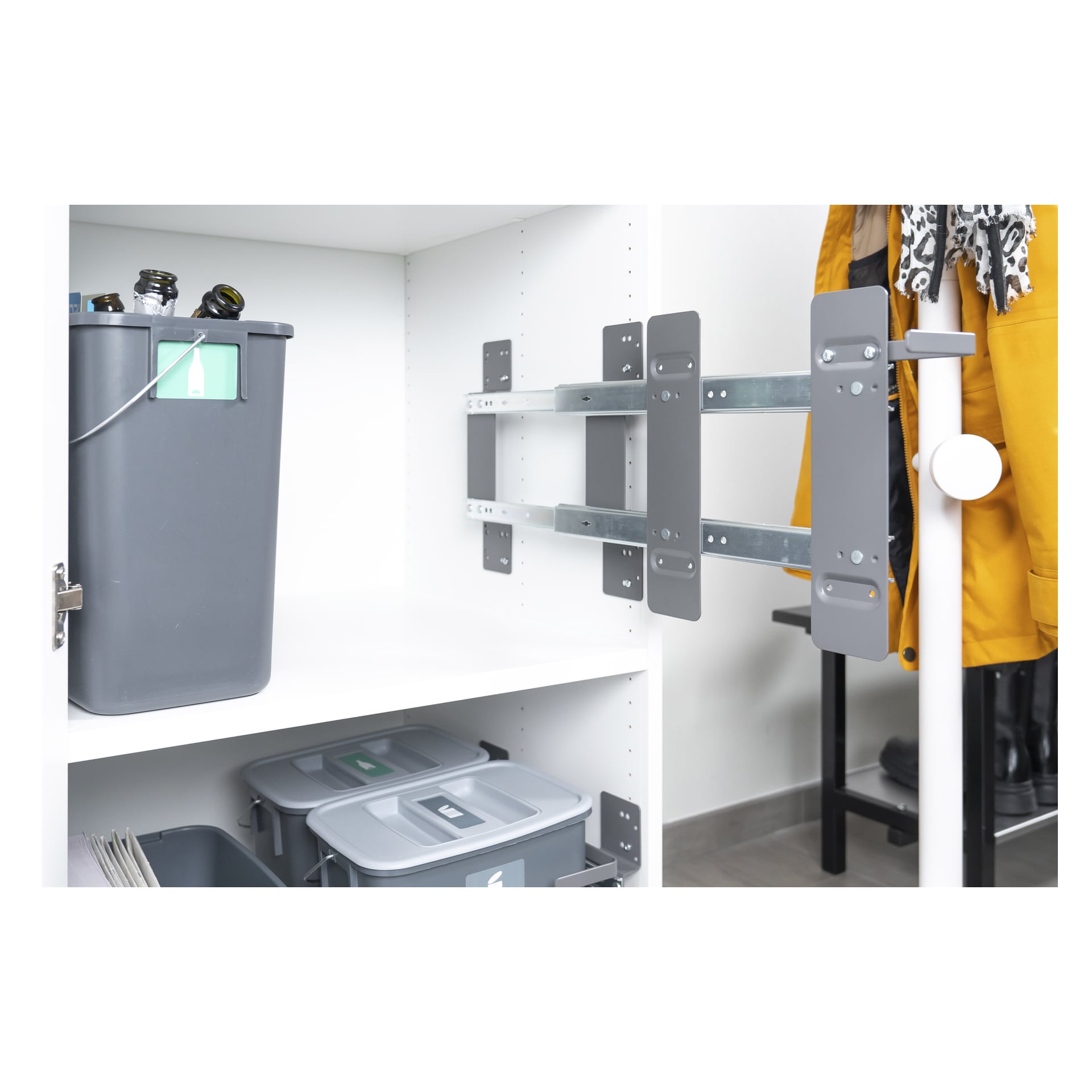 Installerad med sidmonterad metallram har Nordiska Plast Pull-out Sorting at Source 6-delat system en stor grå återvinningskärl på en övre utfällbar hylla och två mindre grå behållare under. En gul rock hänger i närheten, och en vit stång är placerad till höger.