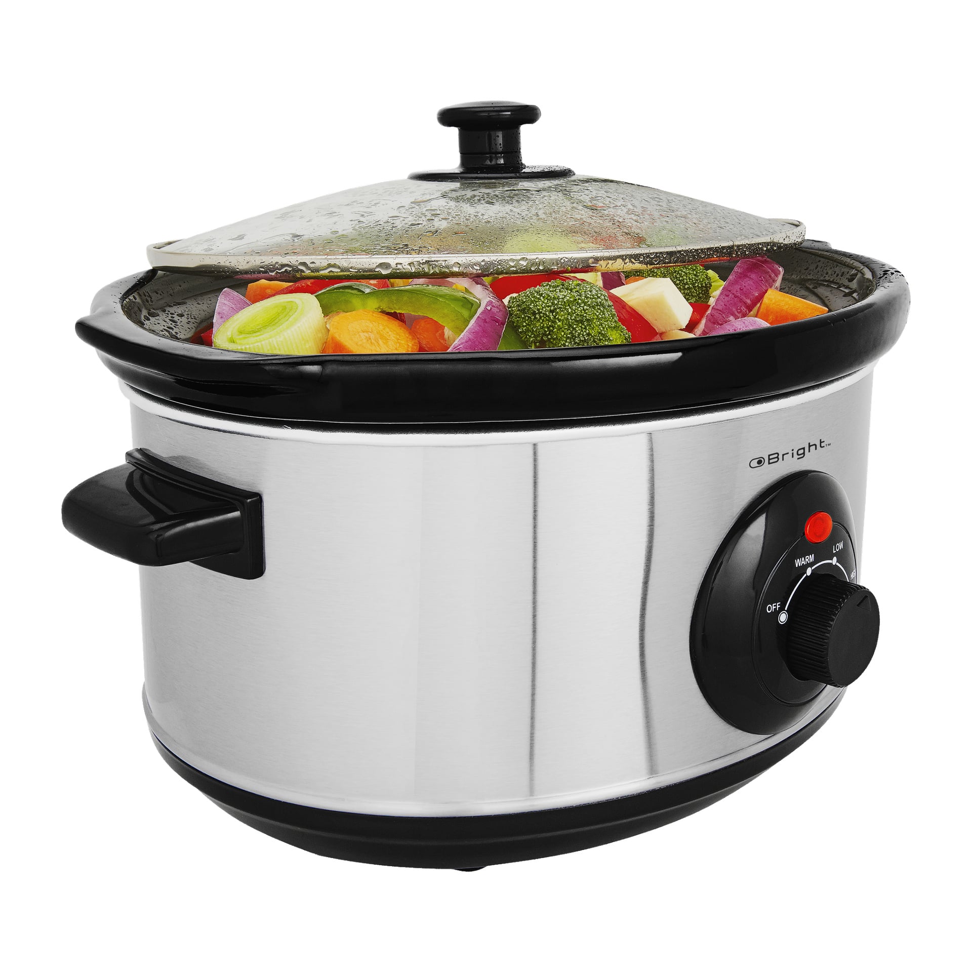 En rostfri stål-Bright Slow Cooker med glaslock är fylld med hackade morötter, broccoli, rödlök och purjolök. Kontrollratten är vriden på låg värme.