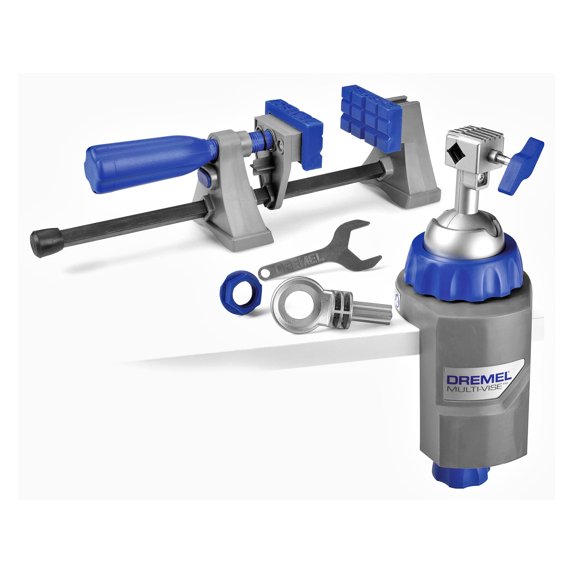 Ett Dremel Tool Holder Multi-Vise 2500-set inkluderar huvudskruvstädenheten med Dremel-logotypen, en klämma, en skiftnyckel, ett cirkulärt fäste och två blå plastdelar.