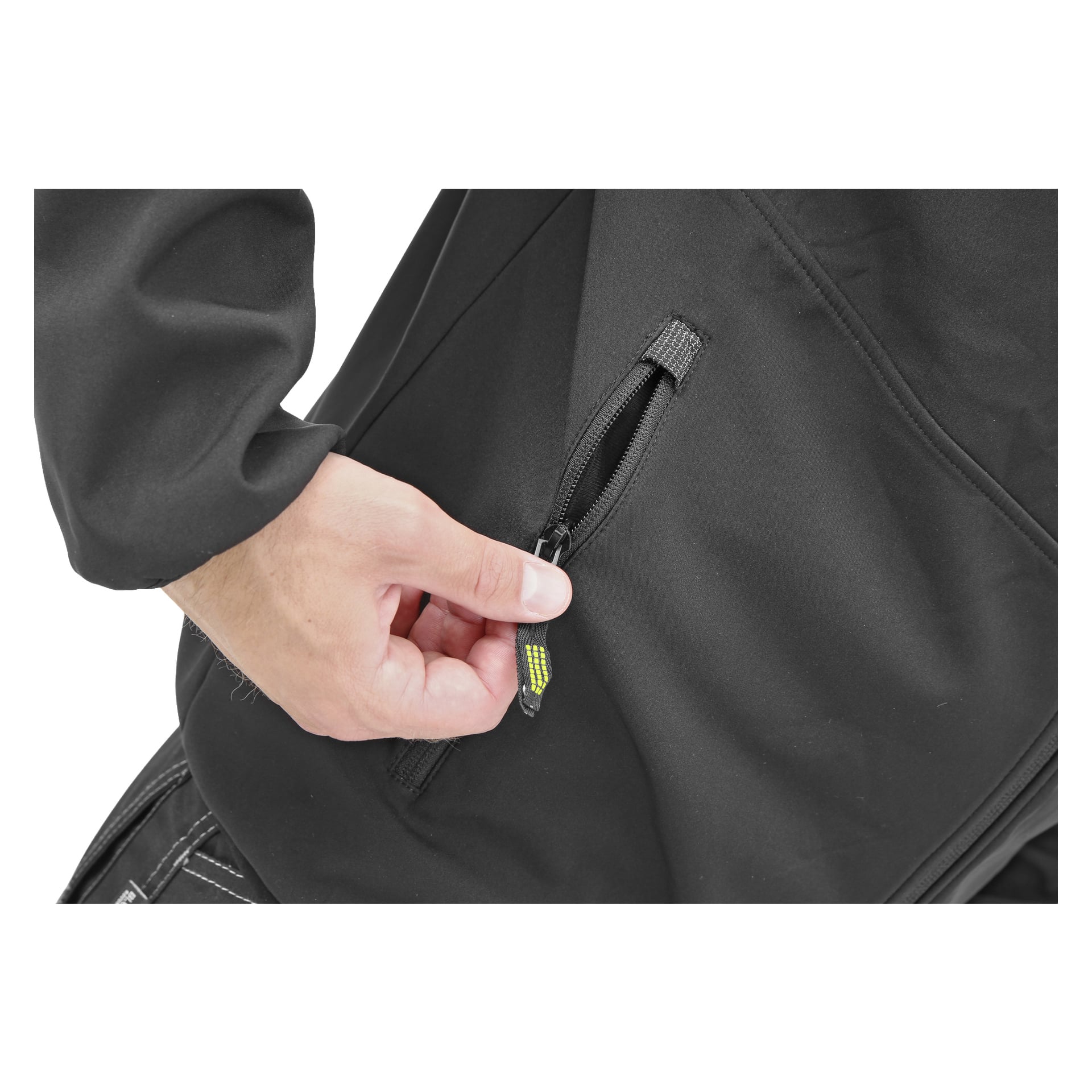 En persons hand öppnar en ficka på Simons herrjacka från Bluewear. Den svarta jackan har synliga sömmar och dragkedja med gröna och grå detaljer. Endast handen och bålen visas.