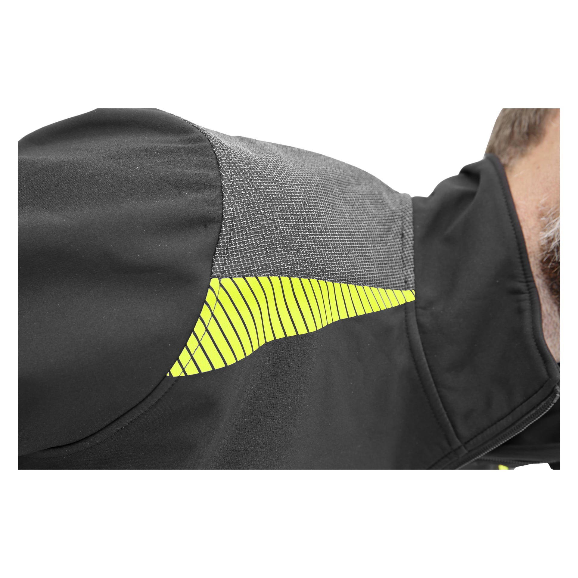 En närbild av någon klädd i Bluewear Men's Simon softshell-jacka, som är svart med en texturerad grå panel på axeln och en livfull gul rand längs övre ryggen. Endast en del av ansiktet och nacken syns på höger sida.