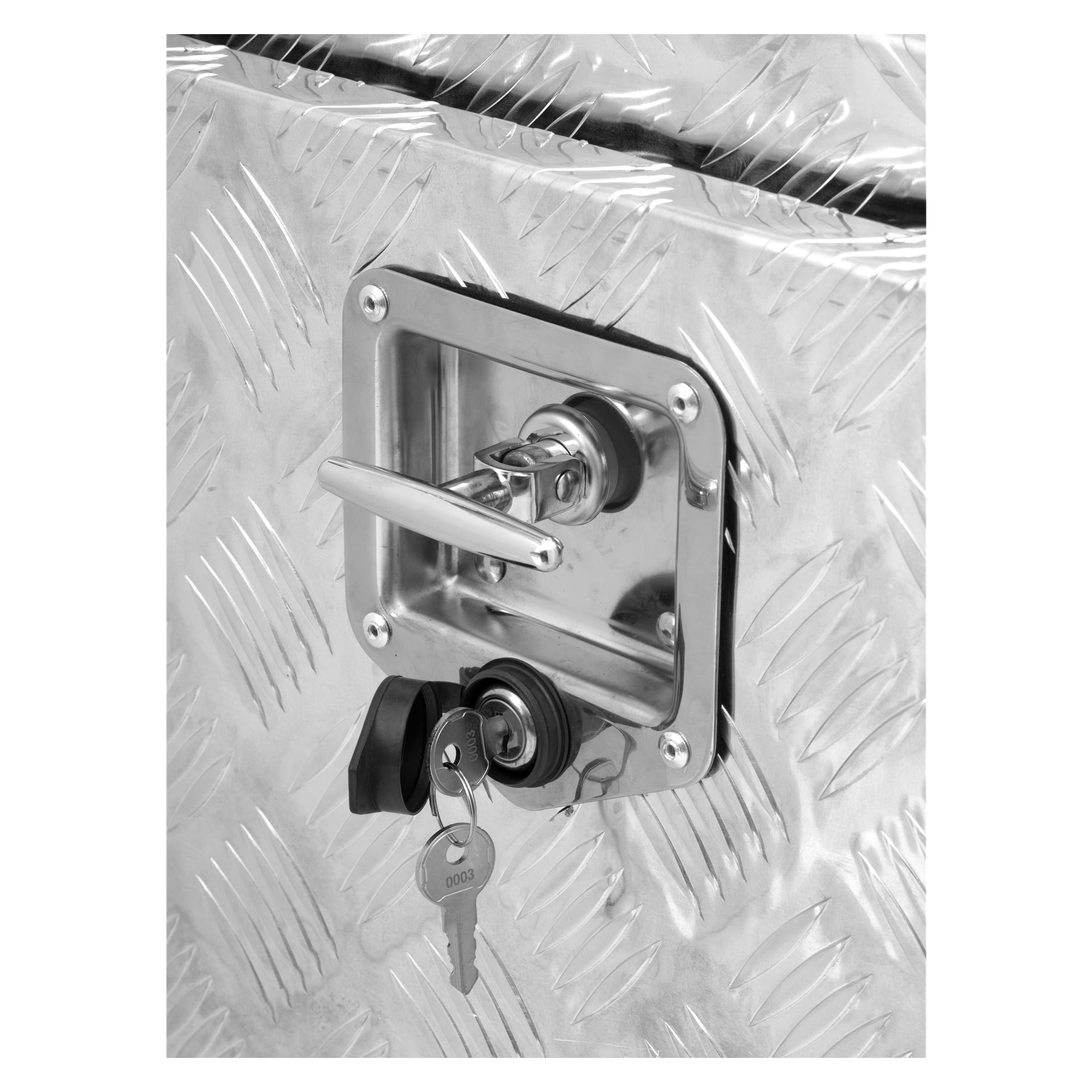 Närbild av en Hard Head aluminiumlåda med ett metallhandtag och lås på dess diamantmönstrade yta, med två nycklar monterade i låset placerade precis under handtaget.