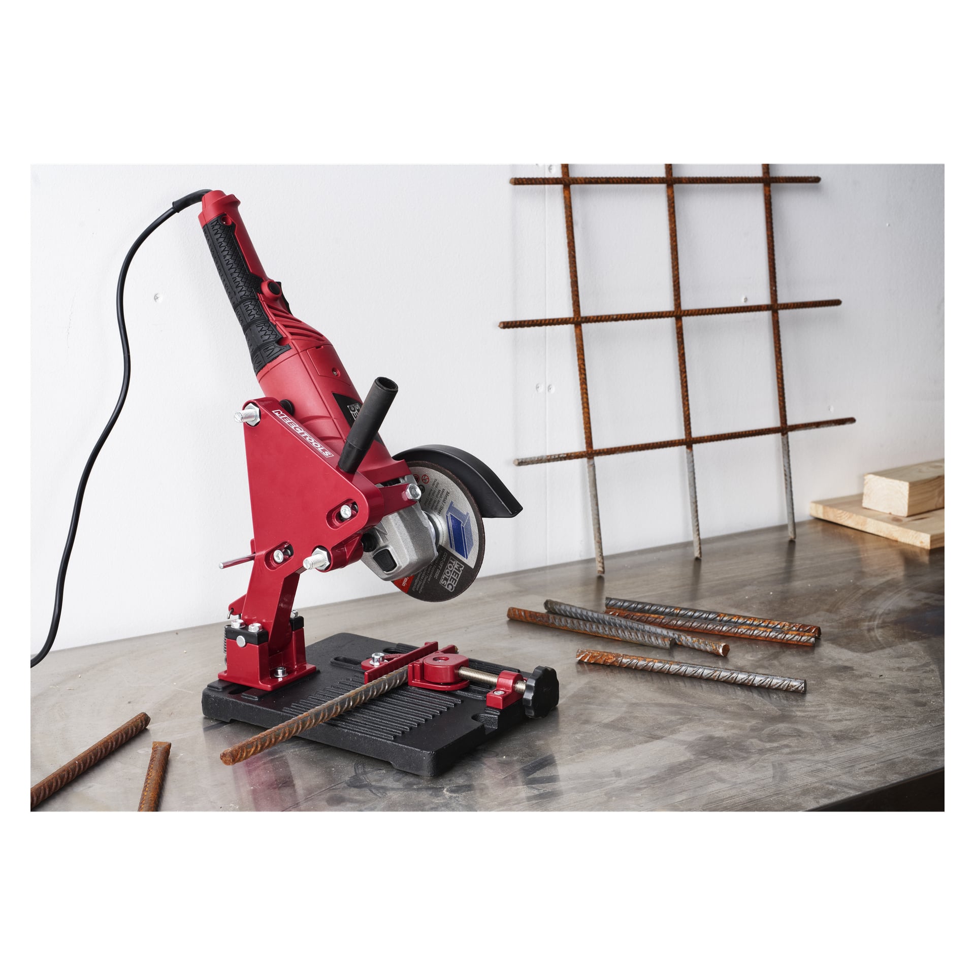 Ett vinkelslipbord från Meec Tools är fäst vid en arbetsbänk, med metallstänger och ett metallgaller i närheten. Träblock kan ses i bakgrunden. Det inkopplade verktyget är inställt redo att användas.