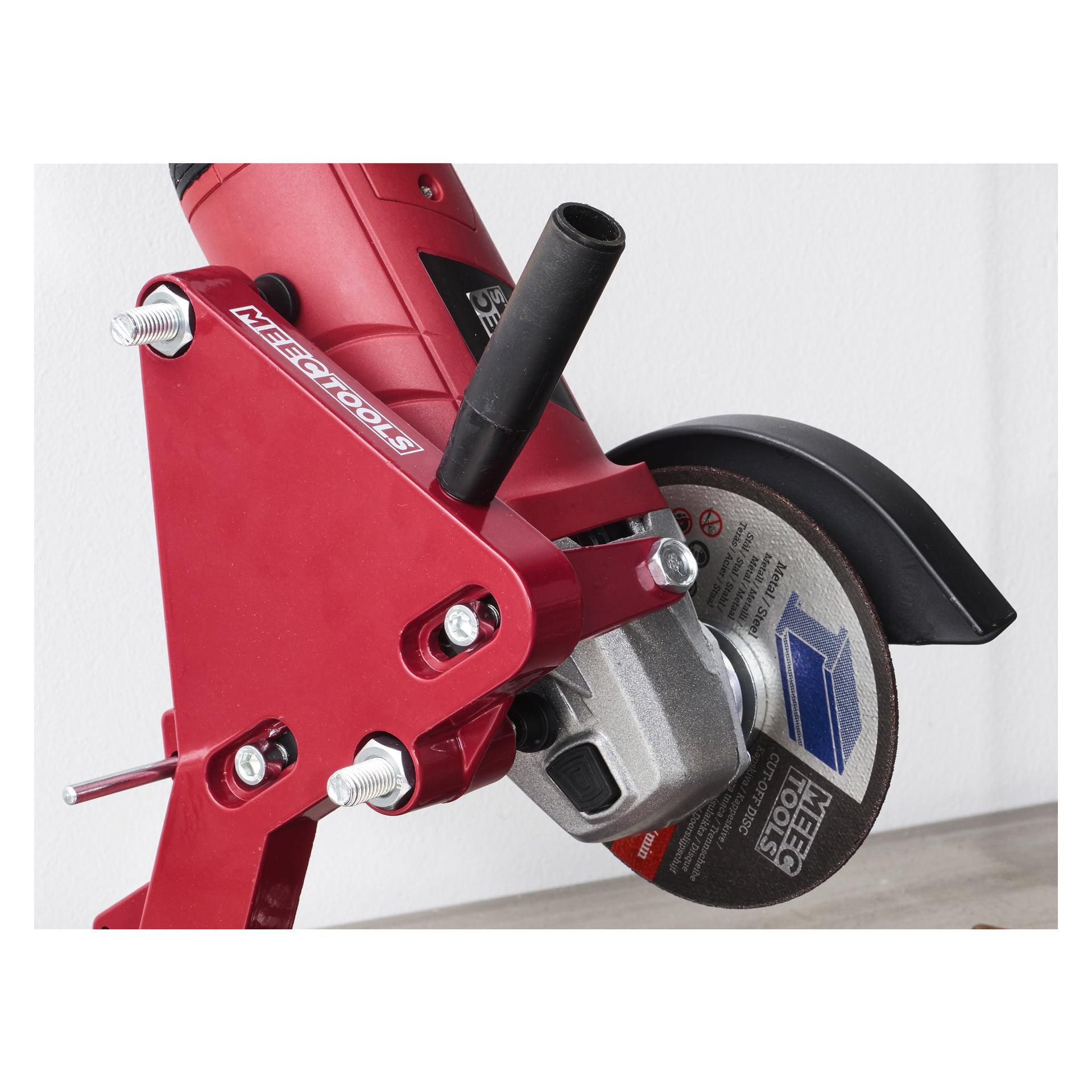 En närbild på ett Meec Tools skärställ som håller en röd vinkelslip från Meec Tools med en exponerad metallskärskiva, svart sidohandtag och flera justeringsbultar fästa.