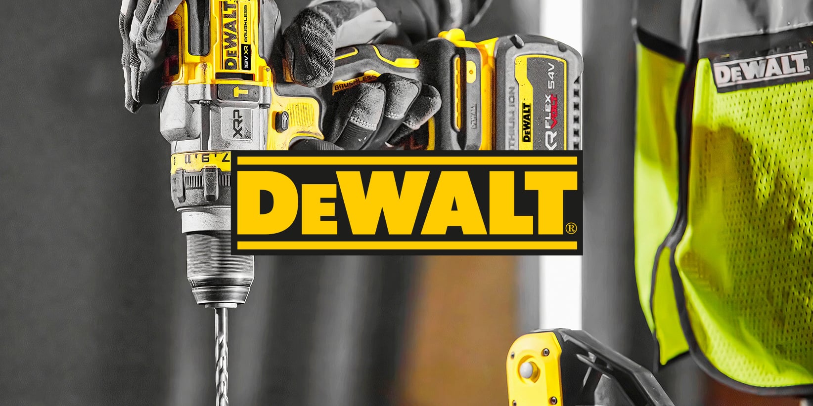 Närbild på en person som använder en gul och svart DeWalt borrmaskin, DeWalt logotyp i mitten av bilden. Ett annat verktyg och en skyddsväst i bakgrunden.