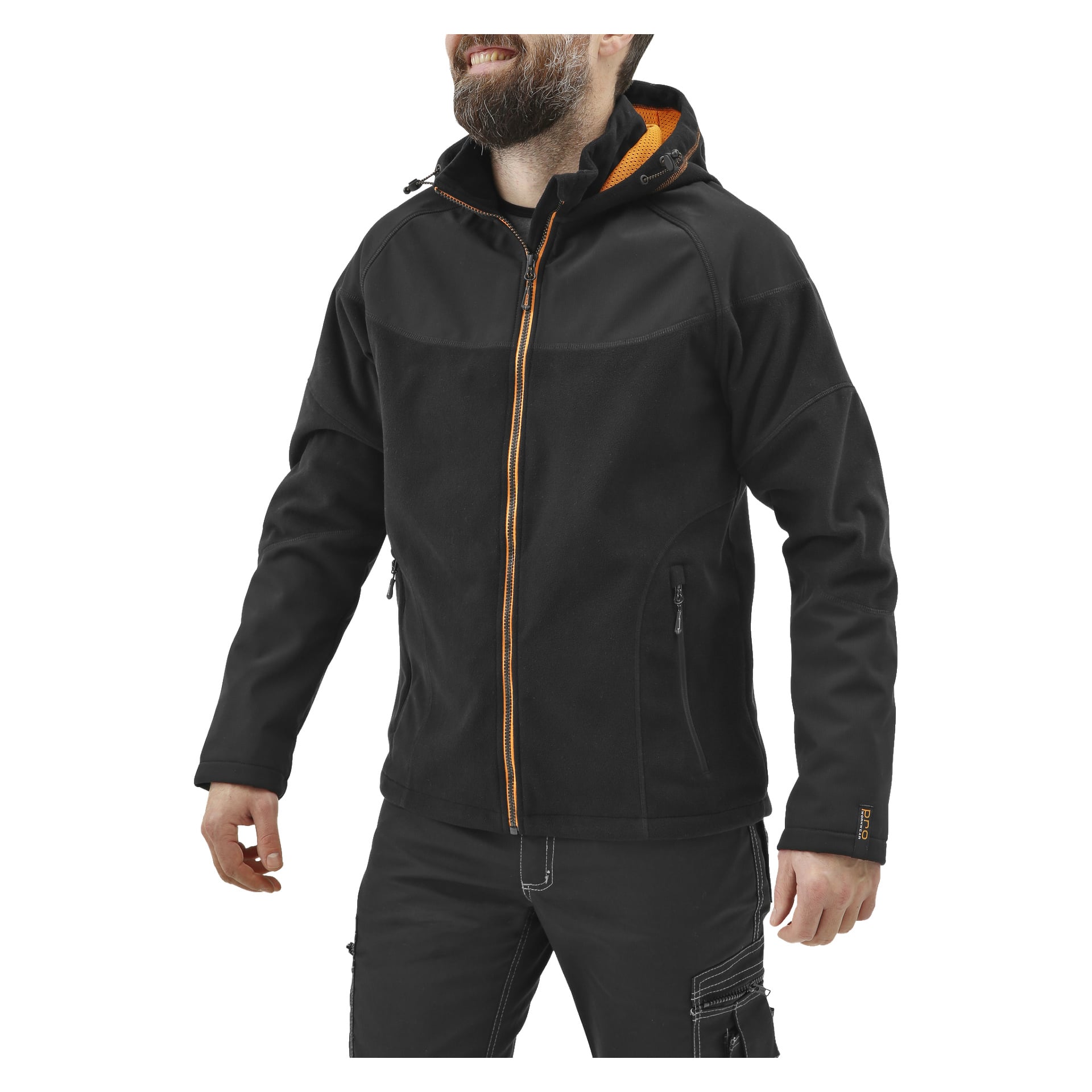 En skäggig man ler och vänder sig lite åt vänster, klädd i en svart Bluewear Pro Workwear herrjacka med vindtät fleecejacka med orange detaljer. Jackan har huva, två fickor med dragkedja, synliga sömmar och bärs med svarta byxor.
