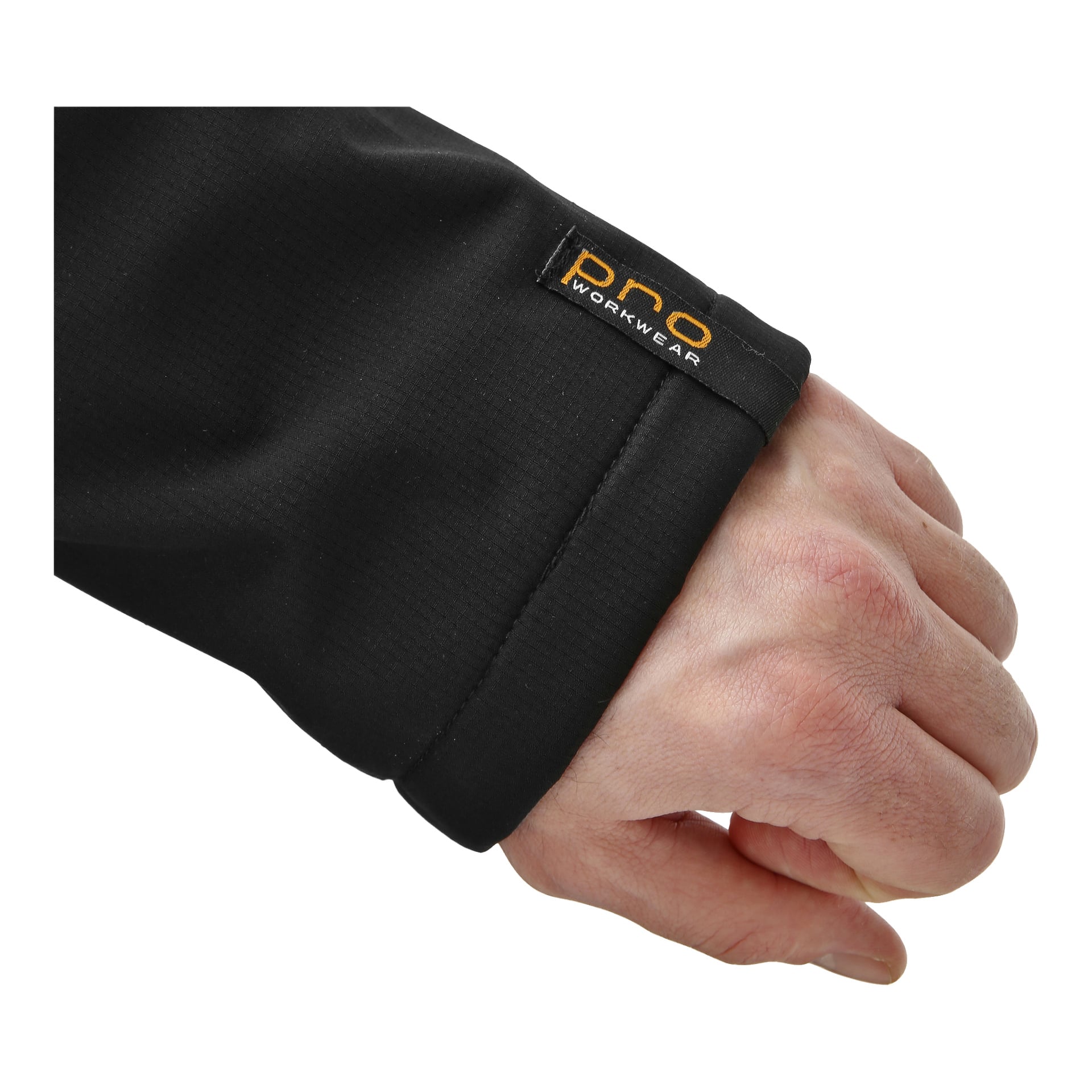 En närbild visar en persons hand och handled som bär herrarnas vindtäta fleecejacka från Bluewear Pro Workwear. Den svarta ärmen innehåller en liten lapp där det står "pro WORKWEAR." Bakgrunden är enkel och fri från distraktioner.