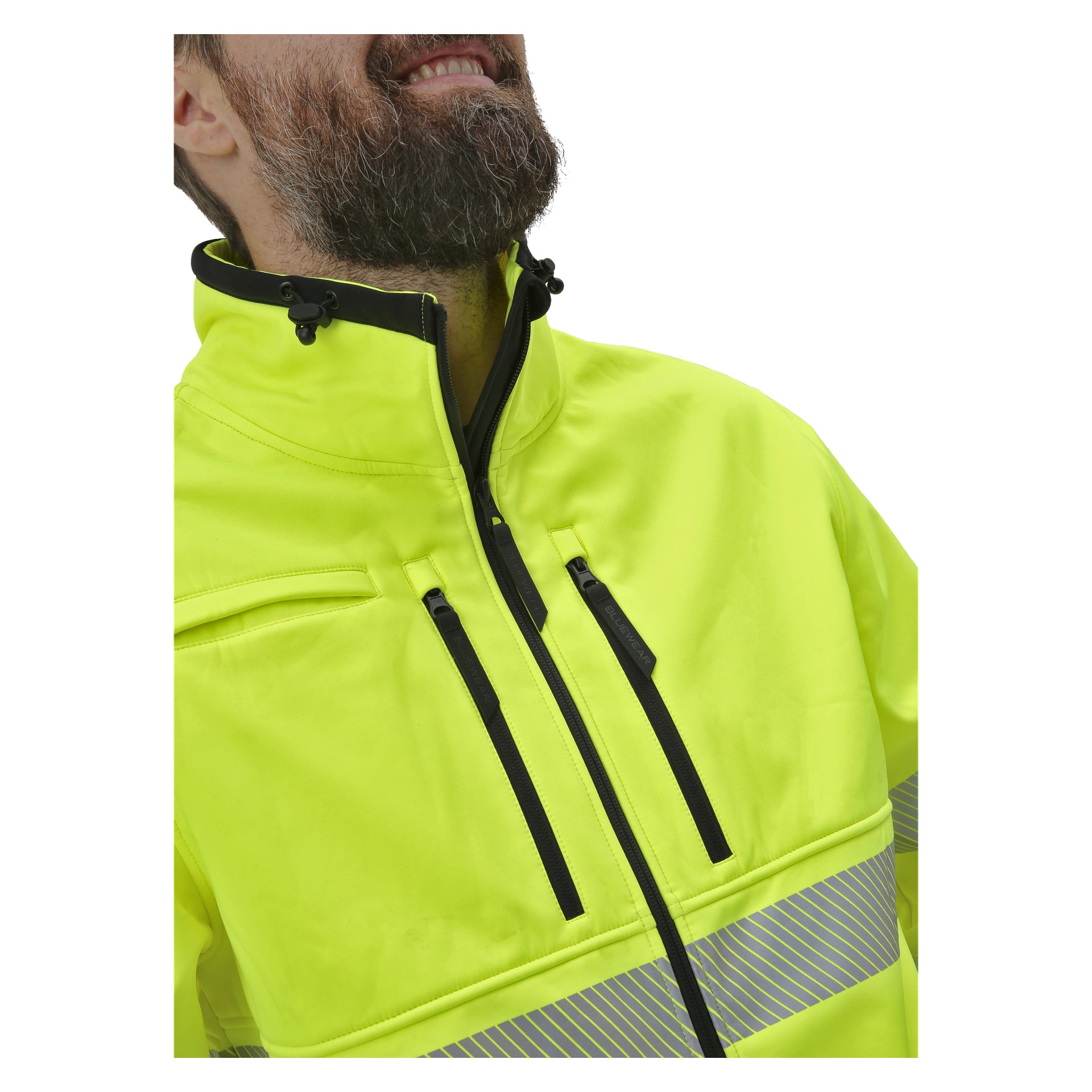 En skäggig man visar Bluewear Hi-Vis softshell-jackan Toronto, som kännetecknas av sin neongula nyans, reflekterande band, dragkedjefickor och höga krage. Endast den nedre halvan av hans ansikte och överkroppen syns på den beskurna bilden.