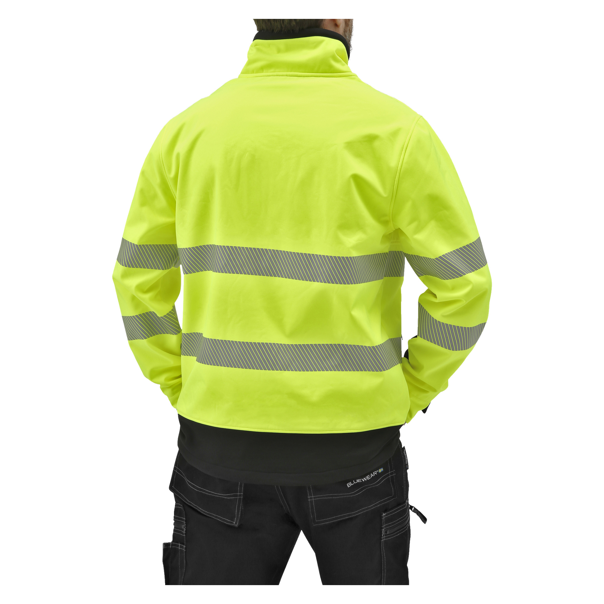 En person syns bakifrån, klädd i Bluewear Hi-Vis softshelljacka Toronto, en färgstark gul jacka med två horisontella reflekterande band och en stående krage, tillsammans med svarta byxor. Deras händer är nedstoppade i fickorna.