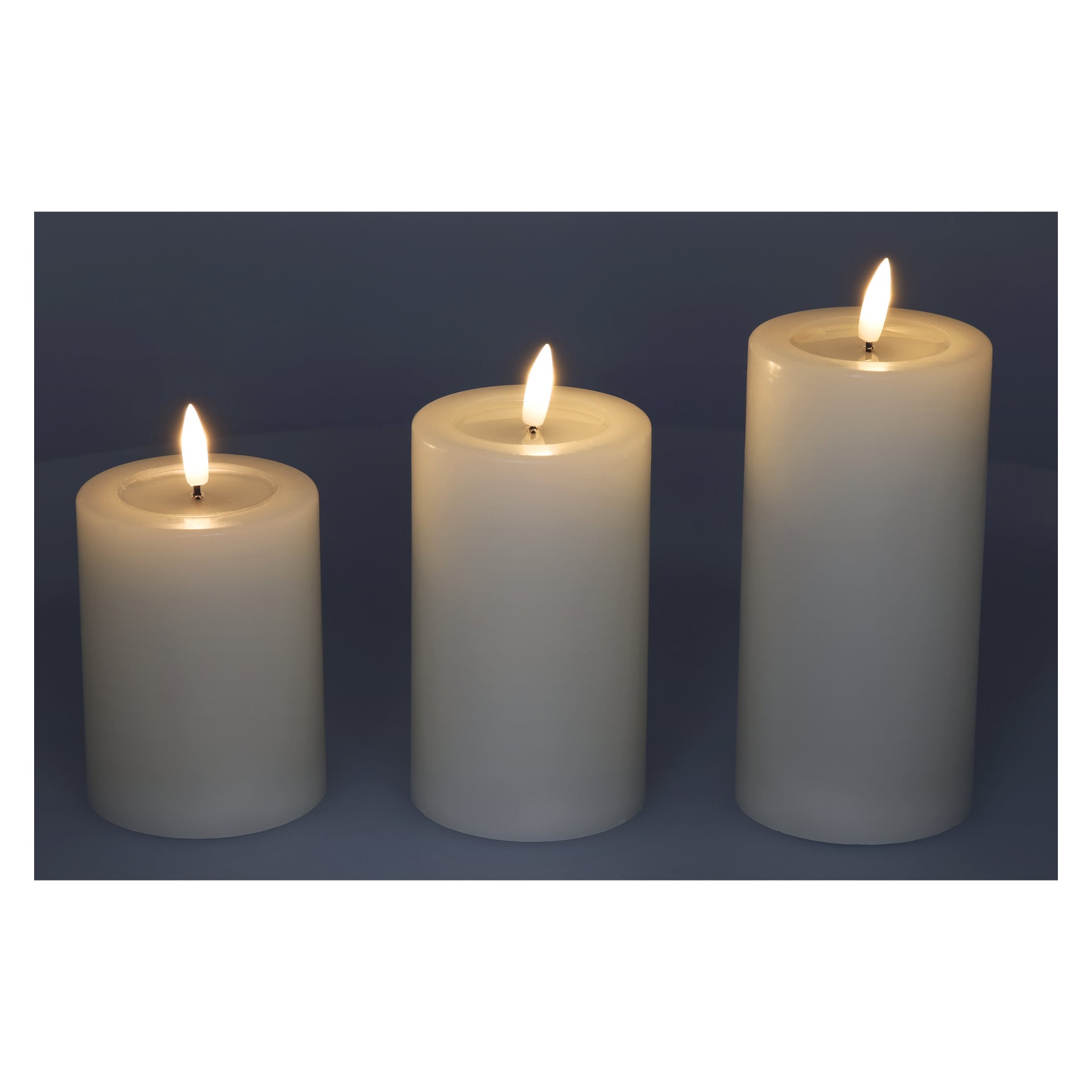 Three Pillar Candle med fladdrande LED-låga – tre delar av Menuett är tända och placerade bredvid varandra mot en mörk bakgrund.