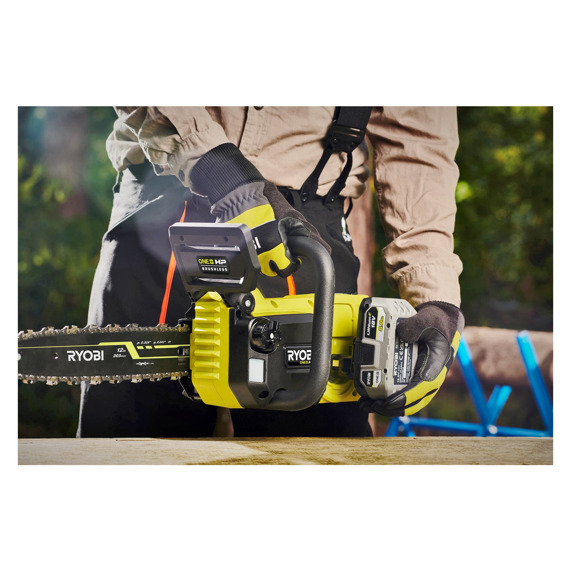 En person med handskar sätter ett batteri i en gul och svart motorsåg märkt RY18CSX30A-0 av Ryobi One+ utanför, med en träyta och ett blått föremål i bakgrunden.