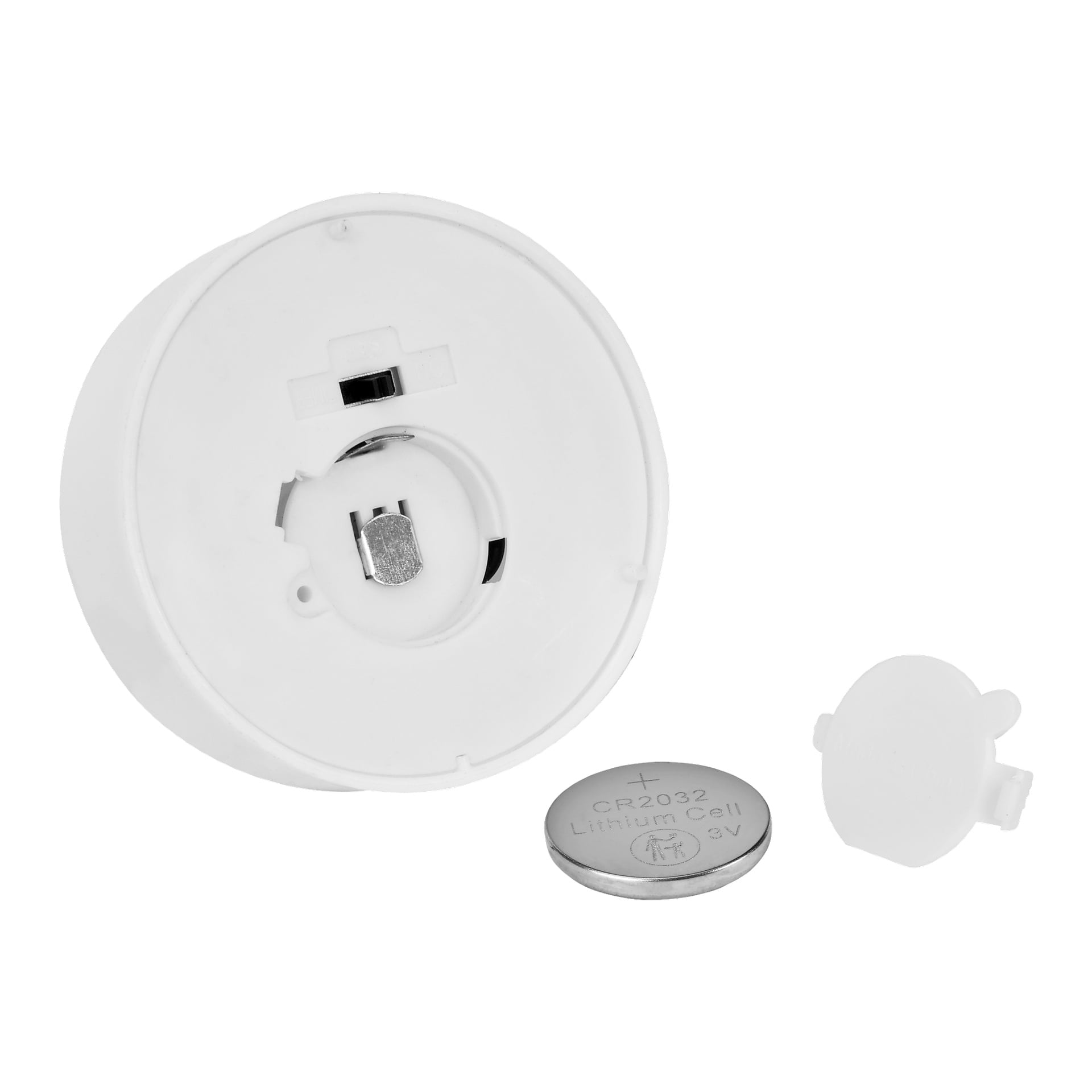 Ett stort Menuett-teljus med en fladdrande LED-låga visas, med batterifacket öppet. Bredvid teljuset finns ett CR2032 litiumbatteri och ett litet vitt plastlock.
