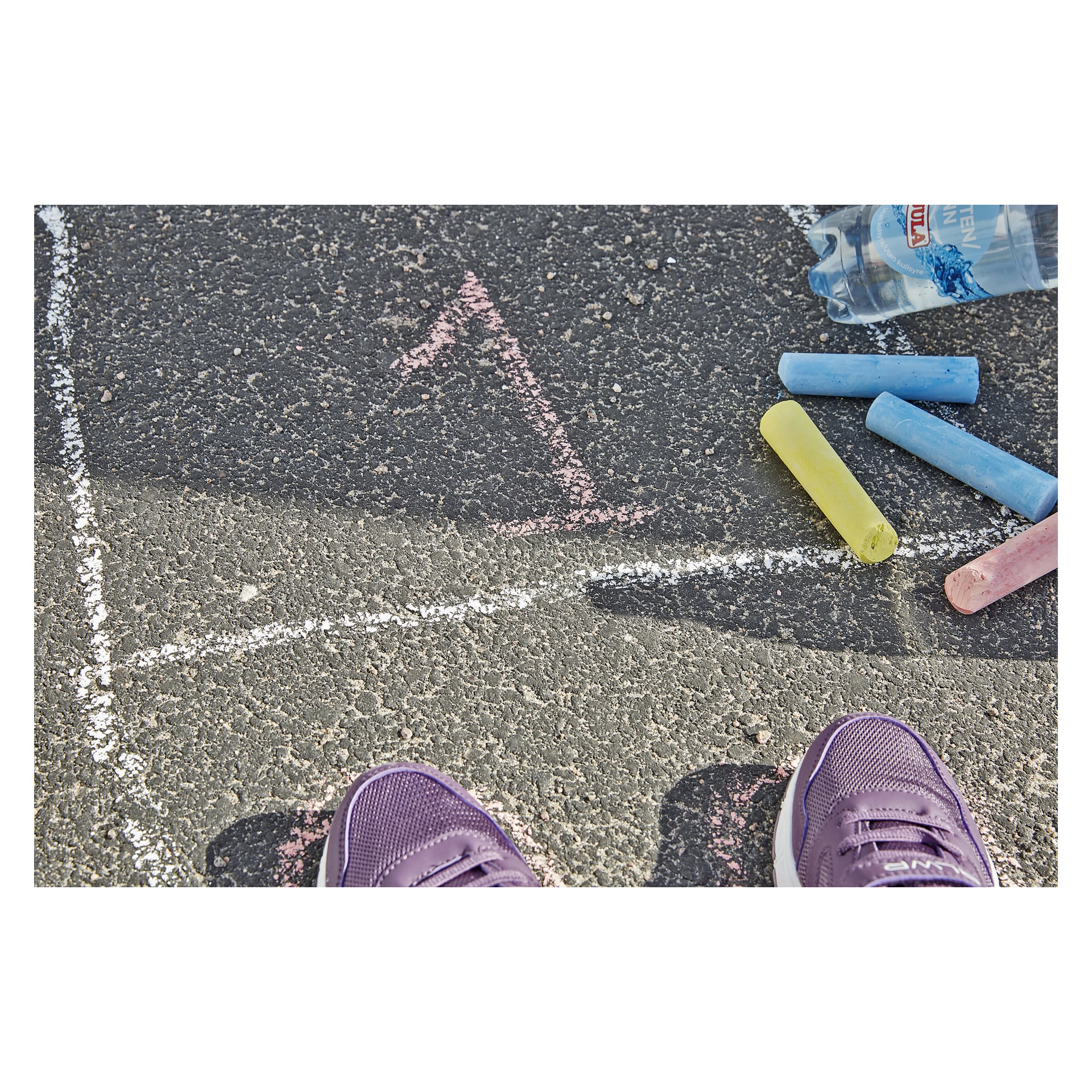 Lila sneakers är placerade på asfalt dekorerade med kritteckningar, varav en med en siffra ett inuti en ruta. I närheten finns flera färgade kritbitar från Kayoba Street Chalks 20 Pack och en vattenflaska.