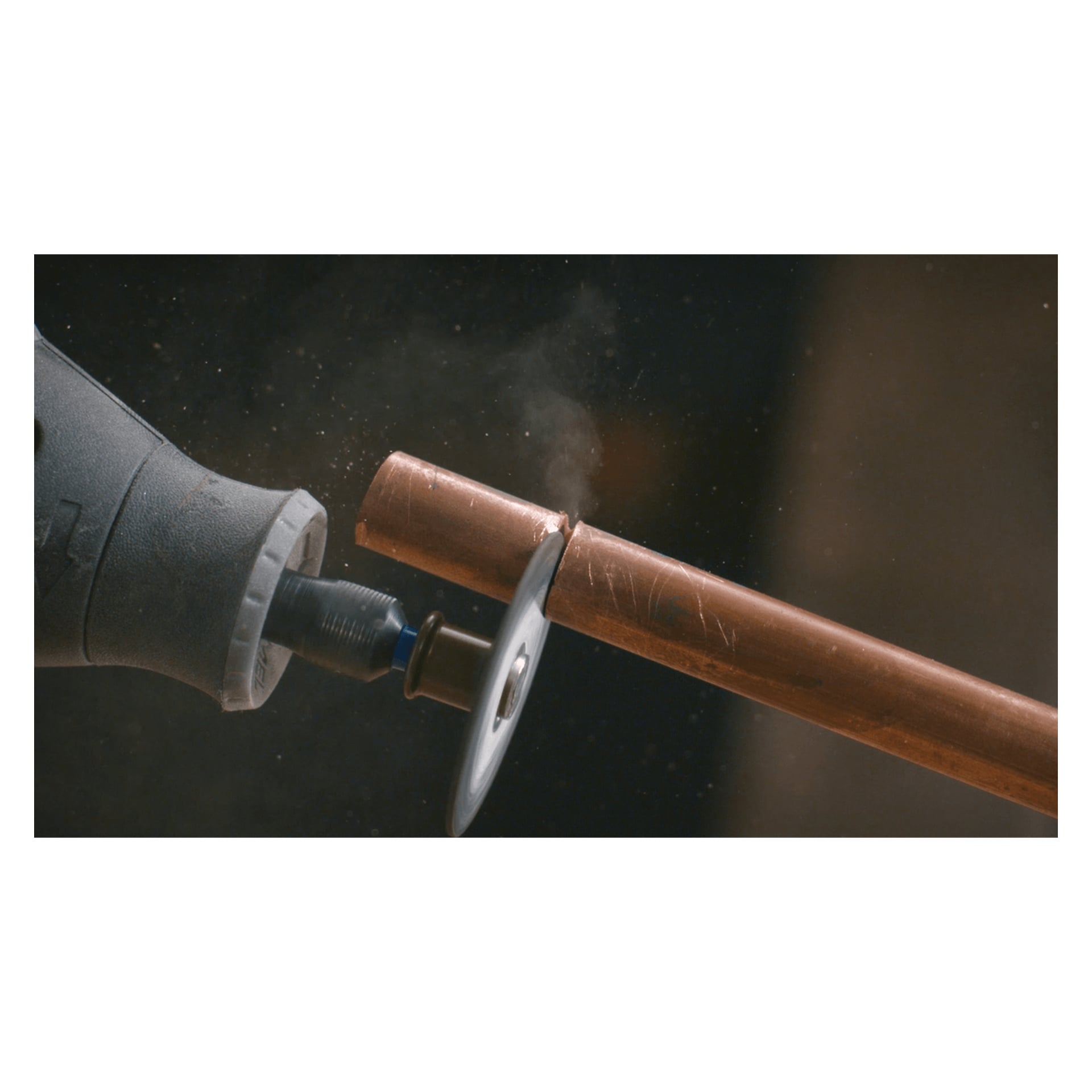 En Dremel SC456 SpeedClic-skärskiva fäst vid ett roterande verktyg skär genom ett kopparrör, vilket producerar gnistor och lite rök när metallen skärs.