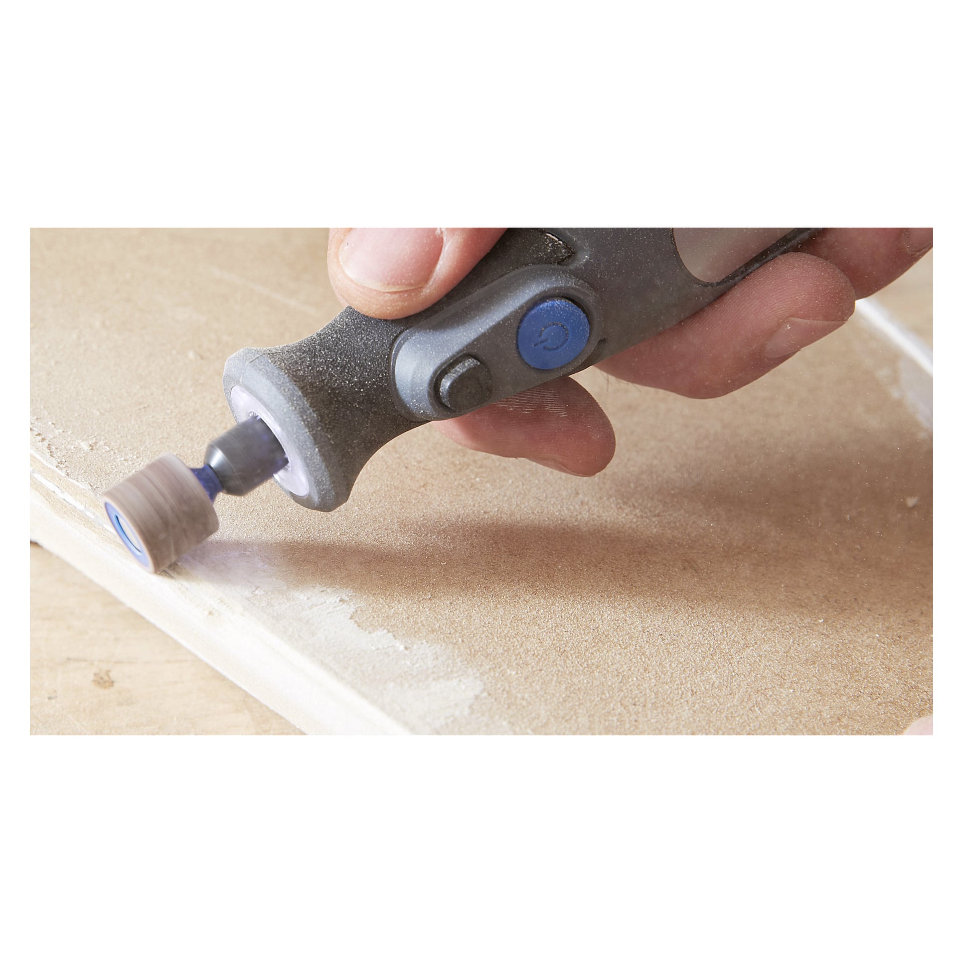 En närbild på en person som slipar kanten på en lätt träbit med ett Dremel-slipband från en sexpack, med handen greppande verktyget medan det slätar ut träet.
