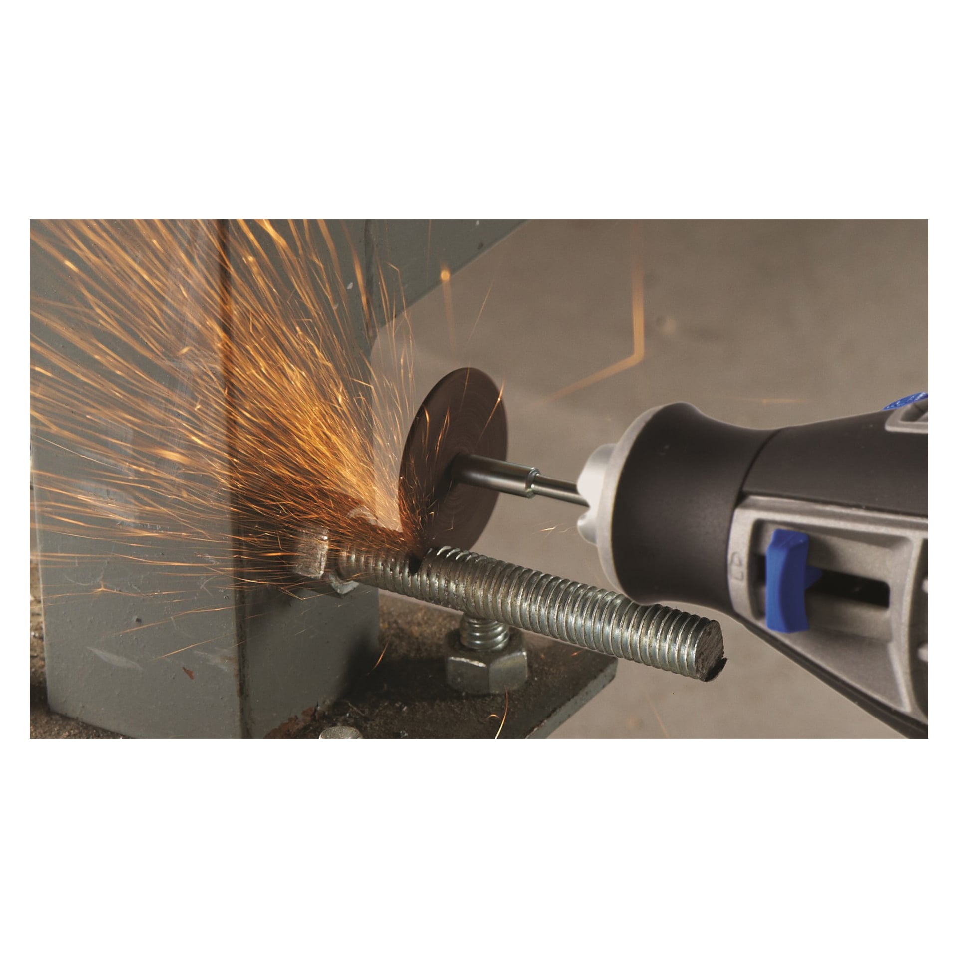 Ett roterande verktyg utrustat med en Dremel 420-skärskiva skär genom en metallbult som är fastsatt med en mutter på en metallyta, vilket skickar klara orange gnistor från där skivan möter metallen.