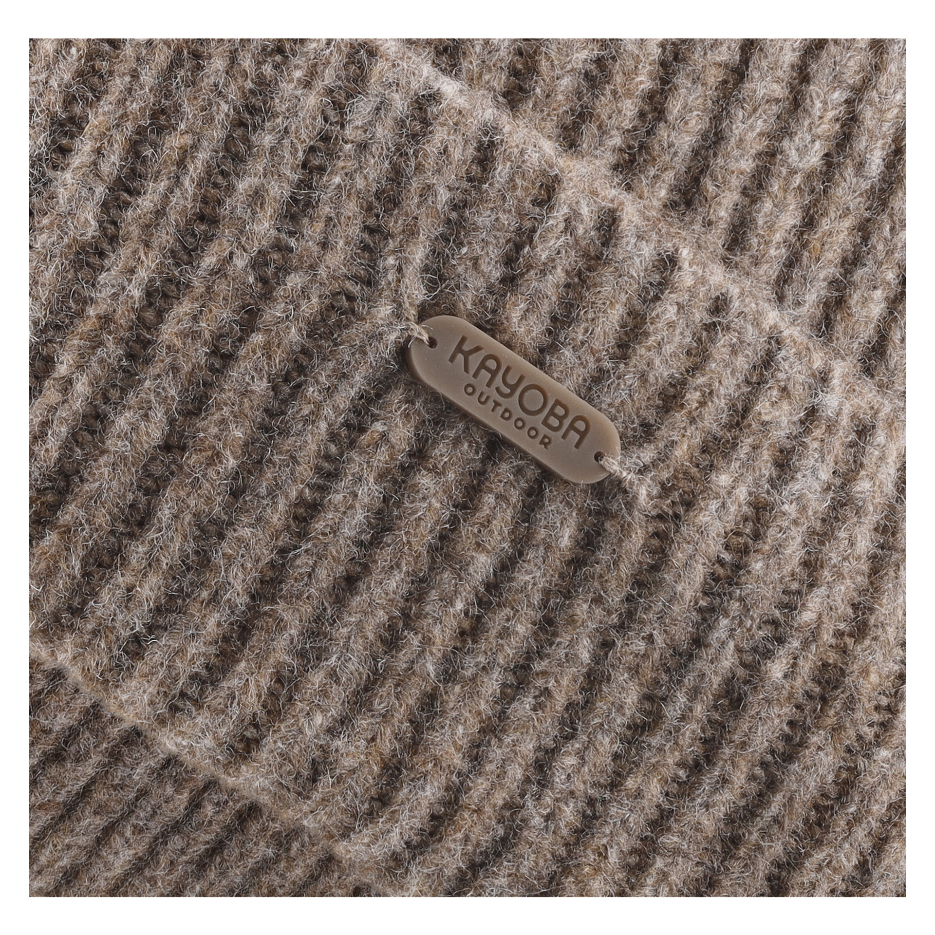 Närbild på en brun stickad mössa med en liten rektangulär lapp där det står Kayoba Outdoor, fastsatt med två trådar.