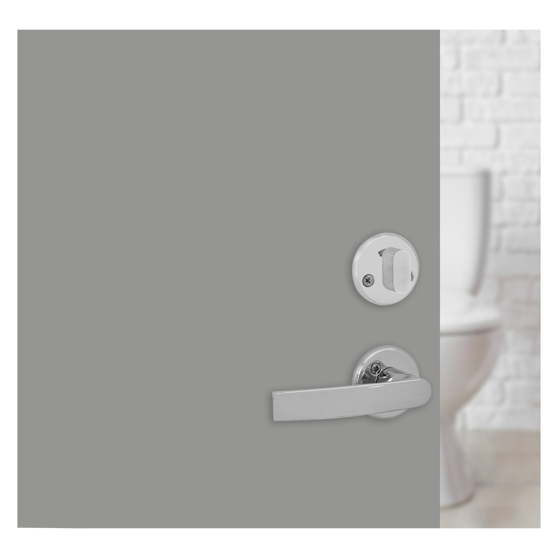 En grå dörr står på glänt, utrustad med ett Hard Head WC-handtag, ett silverhandtag och lås, vilket ger en skymt av en vit toalett och en vit tegelvägg inuti badrummet.