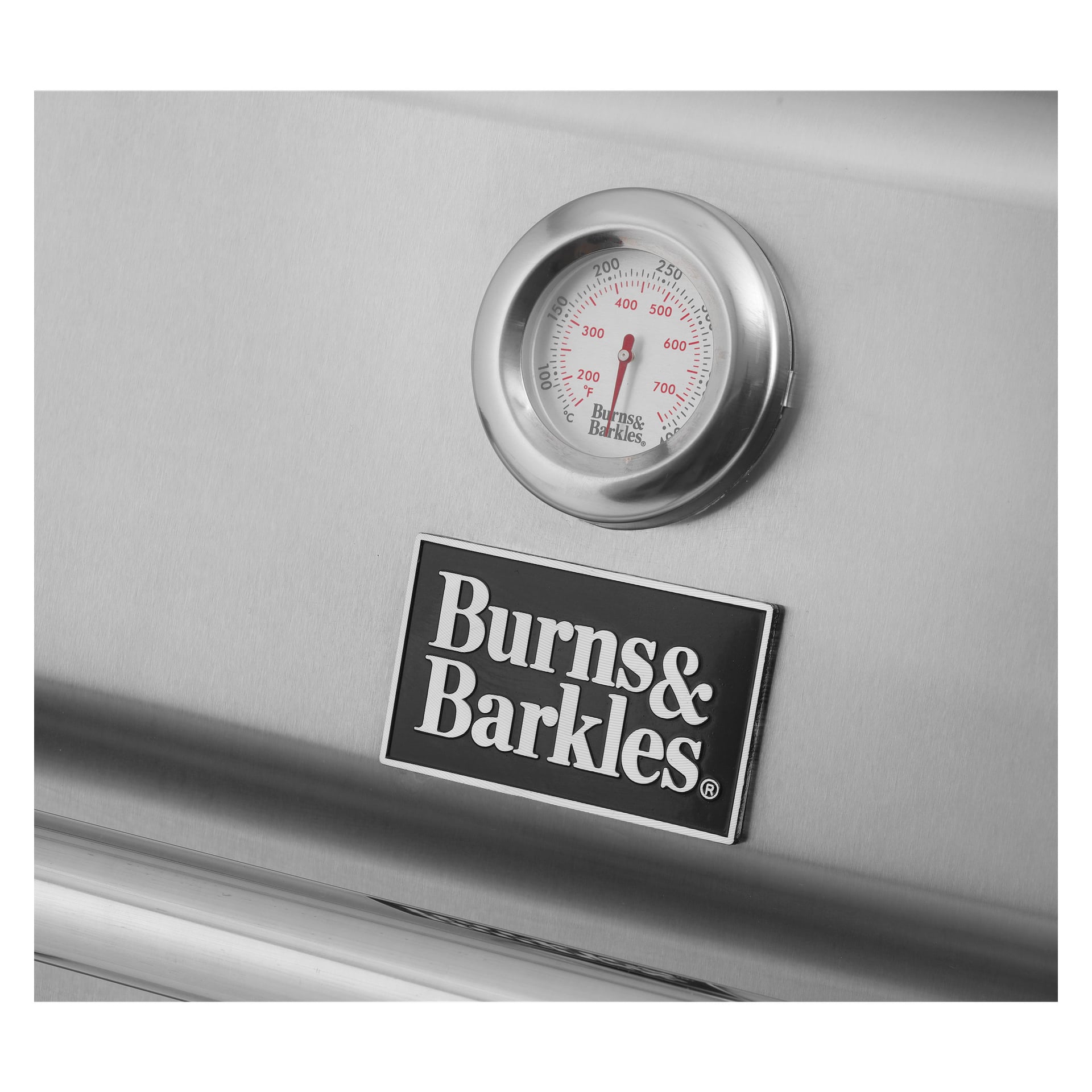 En detaljerad vy av Burns & Barkles Gas Grill Steely King 6342B har en temperaturmätare som visar cirka 200°F, med varumärkeslogotypen placerad precis nedanför. Grillens blanka metallyta ser fläckfri och högpolerad ut.