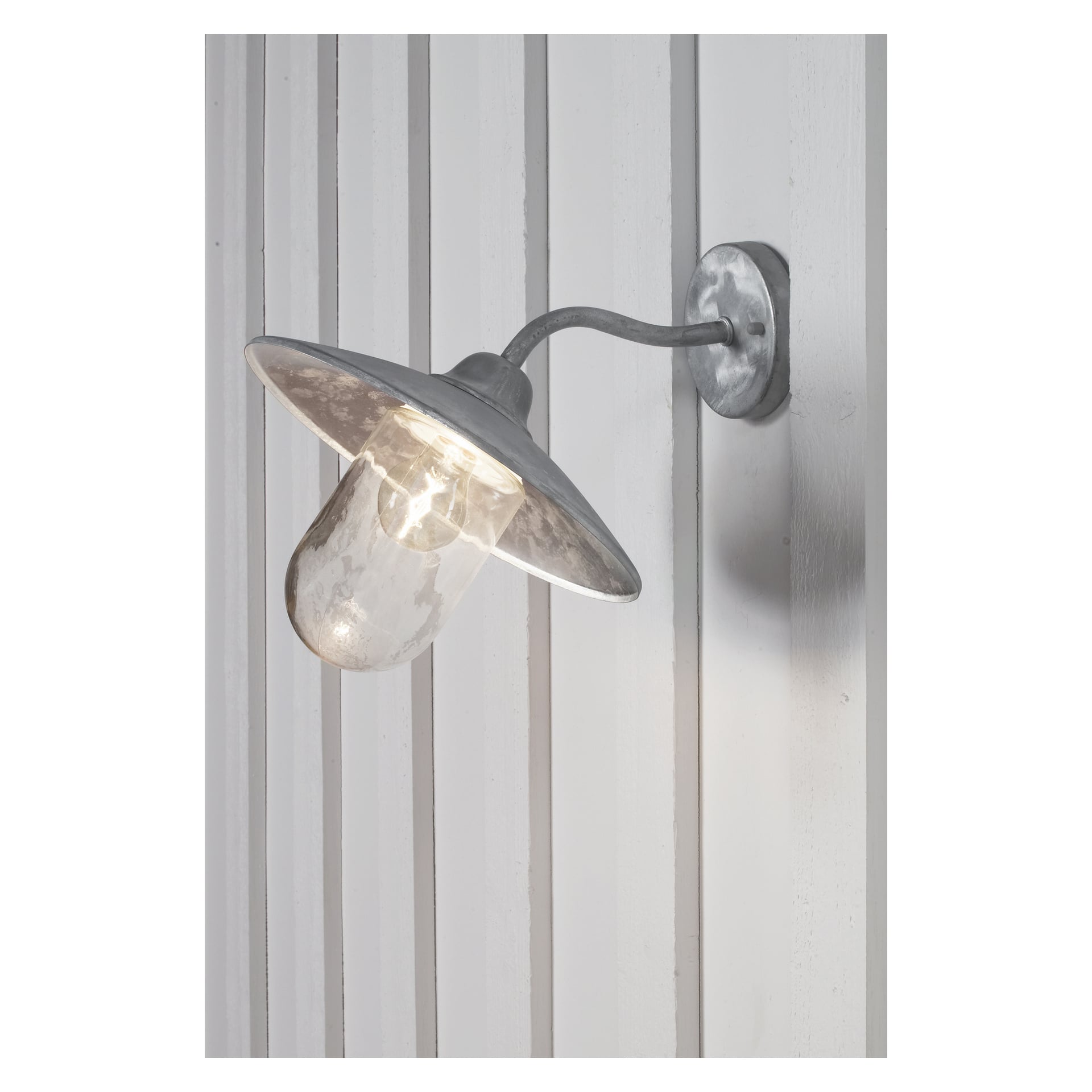 En EKVIP-vägglampa med metallkropp, böjd arm och klar glasskärm är tänd och monterad på en vertikalt panelad vägg.